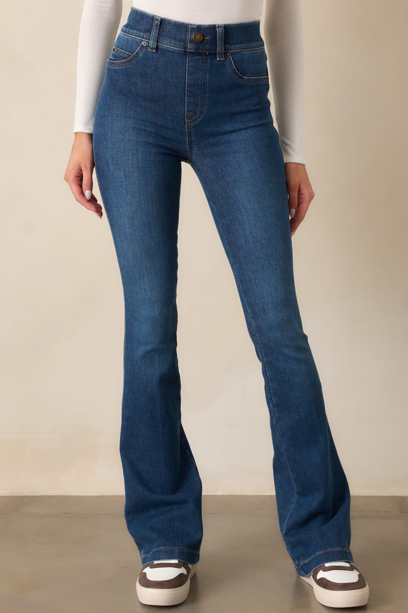 A focused view of the flared hem on the blue jeans, showcasing the smooth fit and stylish silhouette.