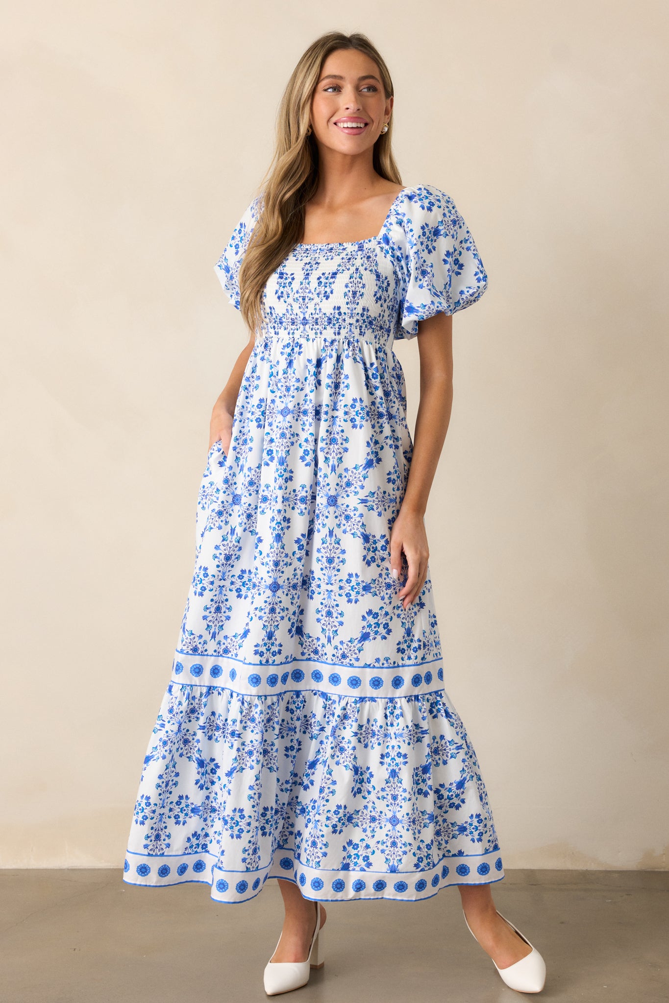 A full view of the royal blue maxi dress featuring a square neckline, smocked top, and relaxed skirt with an intricate floral pattern.