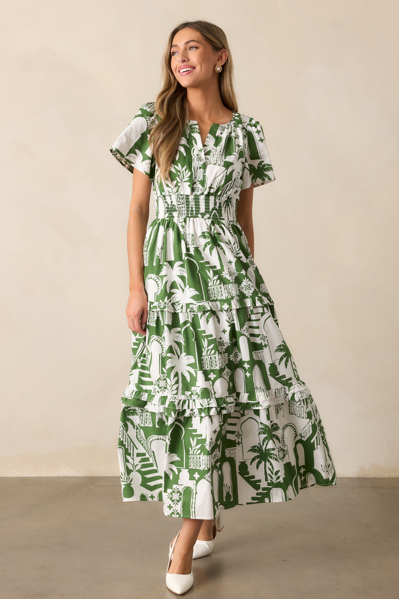 The green dress in a full-length shot, highlighting the smocked waistband, tropical palm print, and tiered skirt.