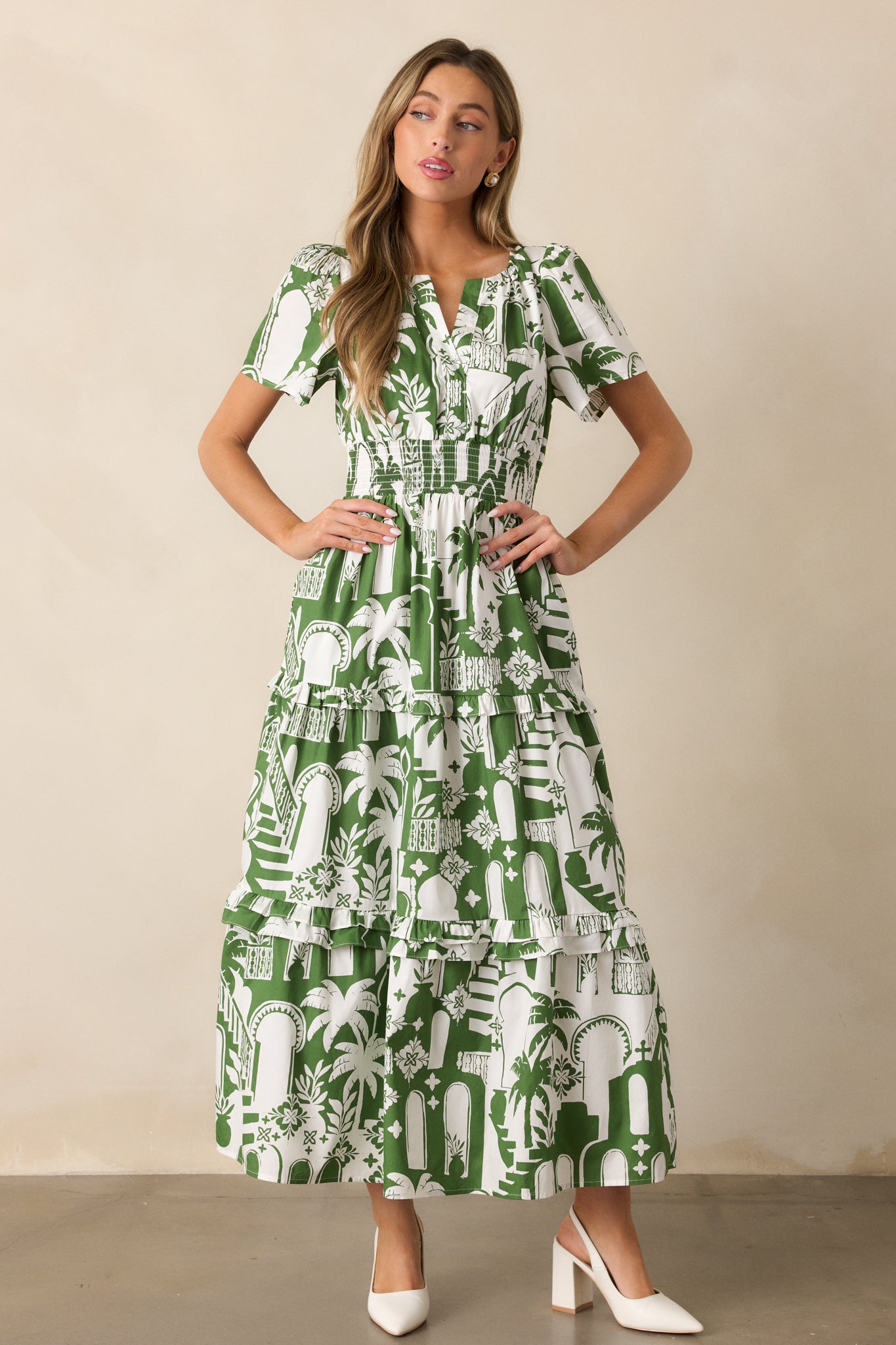 The green dress shown in a full view, showcasing the smocked waistband, tropical print, and short sleeves.