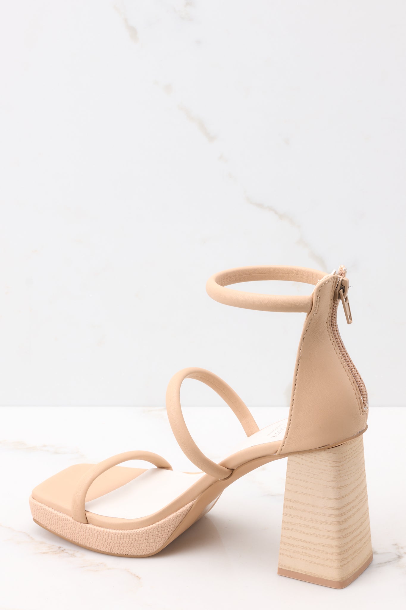 Inner-side view of  these heels that feature a square toe, two straps across the top of the foot with one around the ankle, as well as a block heel and a zipper at the back of the ankle.