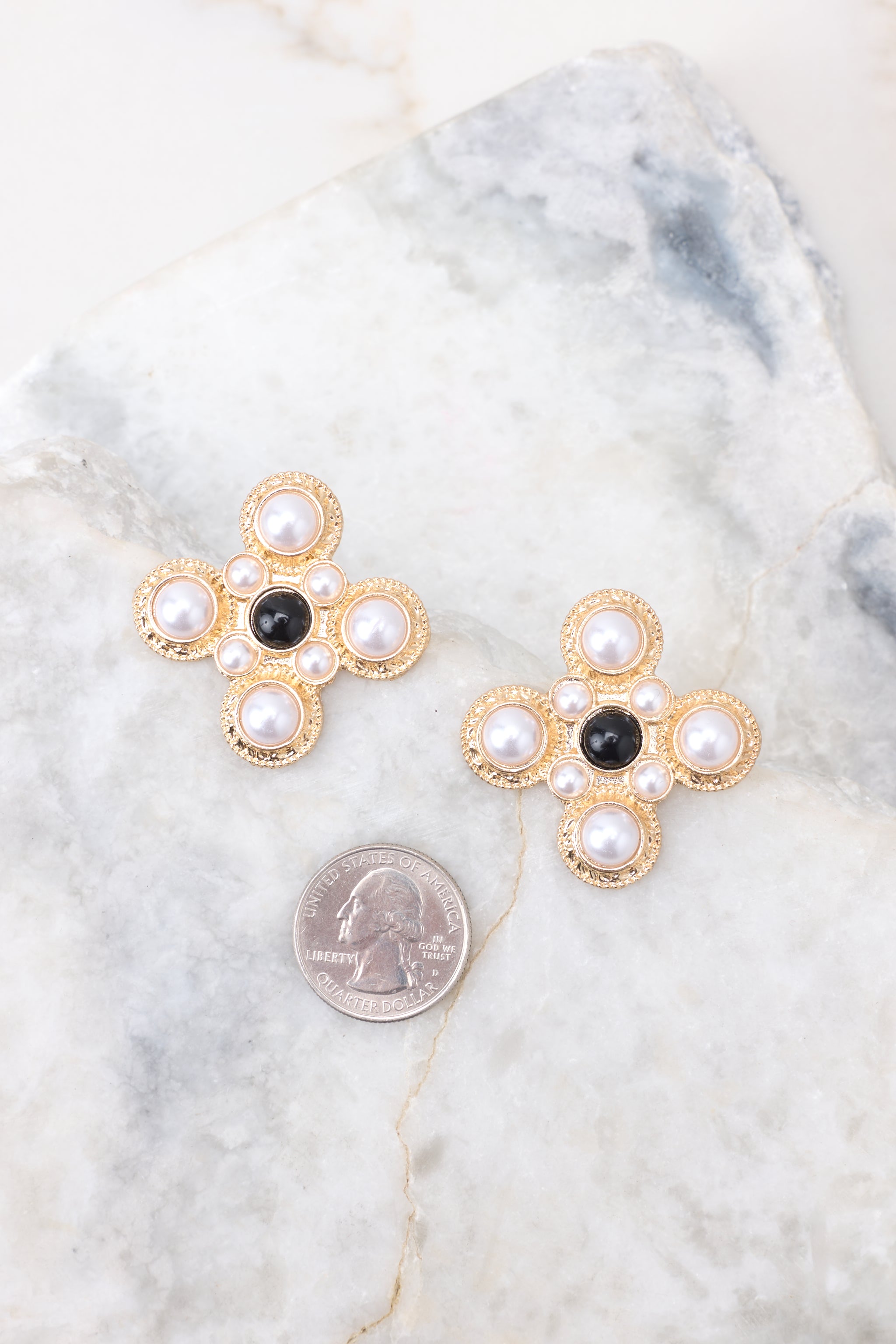 Size comparison of These earrings featuring a fun abstract shape, gold hardware, and white and black pearl detailing.