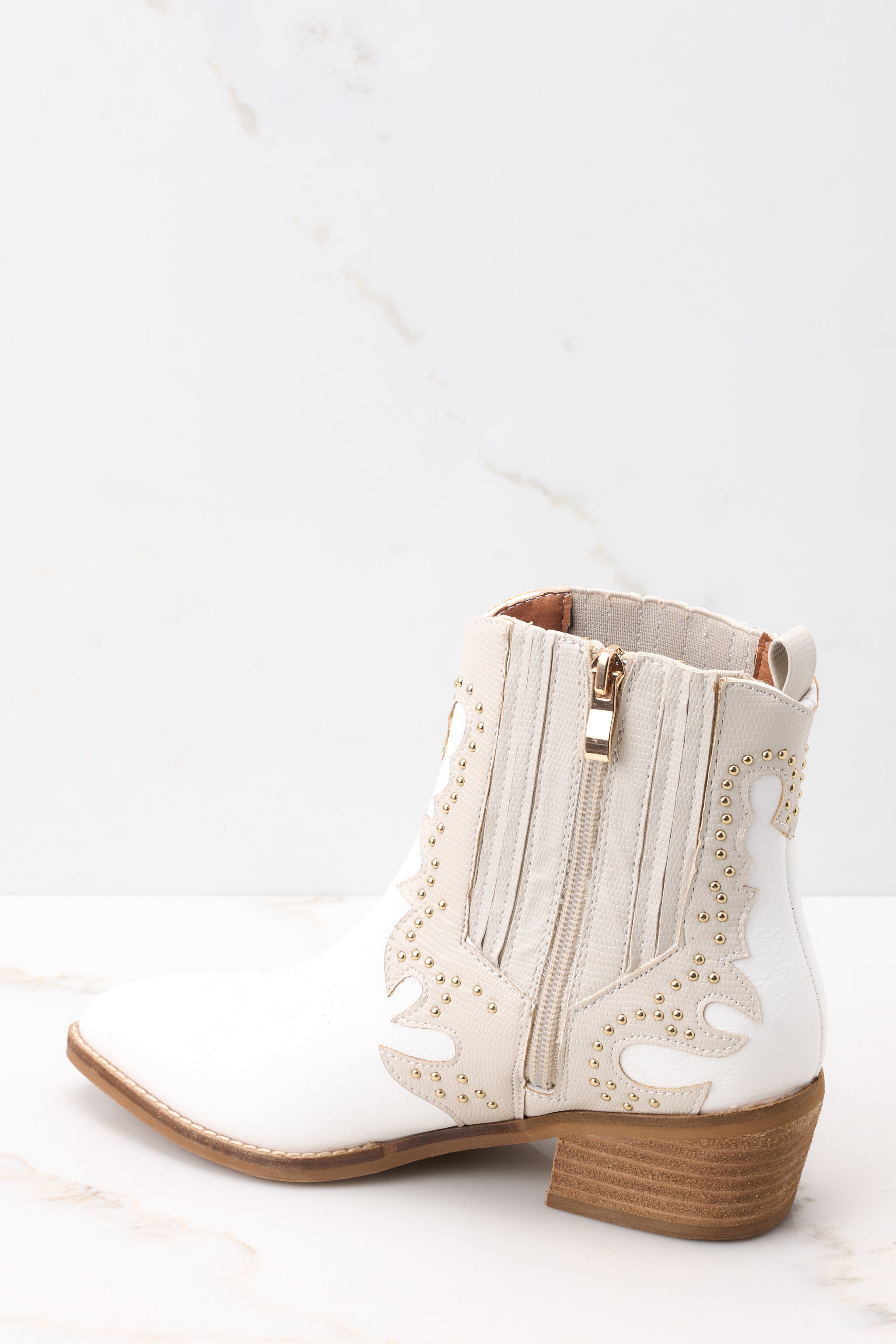 Inner-side view of these ankle boots that feature a pointed toe, a side zipper closure, a stretchy side panel, embroidered detailing, and a stacked heel.