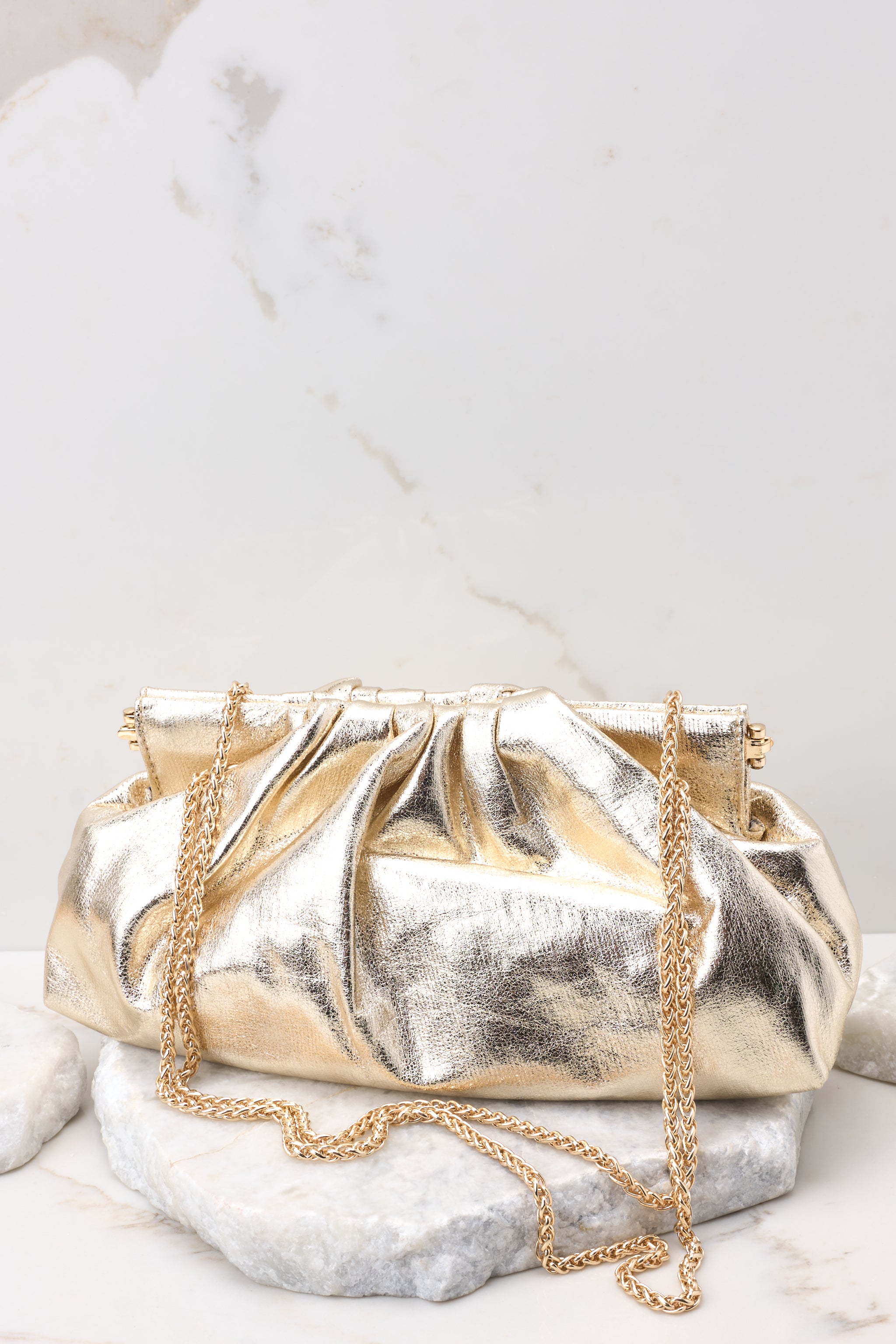 Front view of this bag that features a wide hinged opening that snaps shut (no zipper or snap button closure) , a non-removable gold chain strap, and one zipper pocket inside.