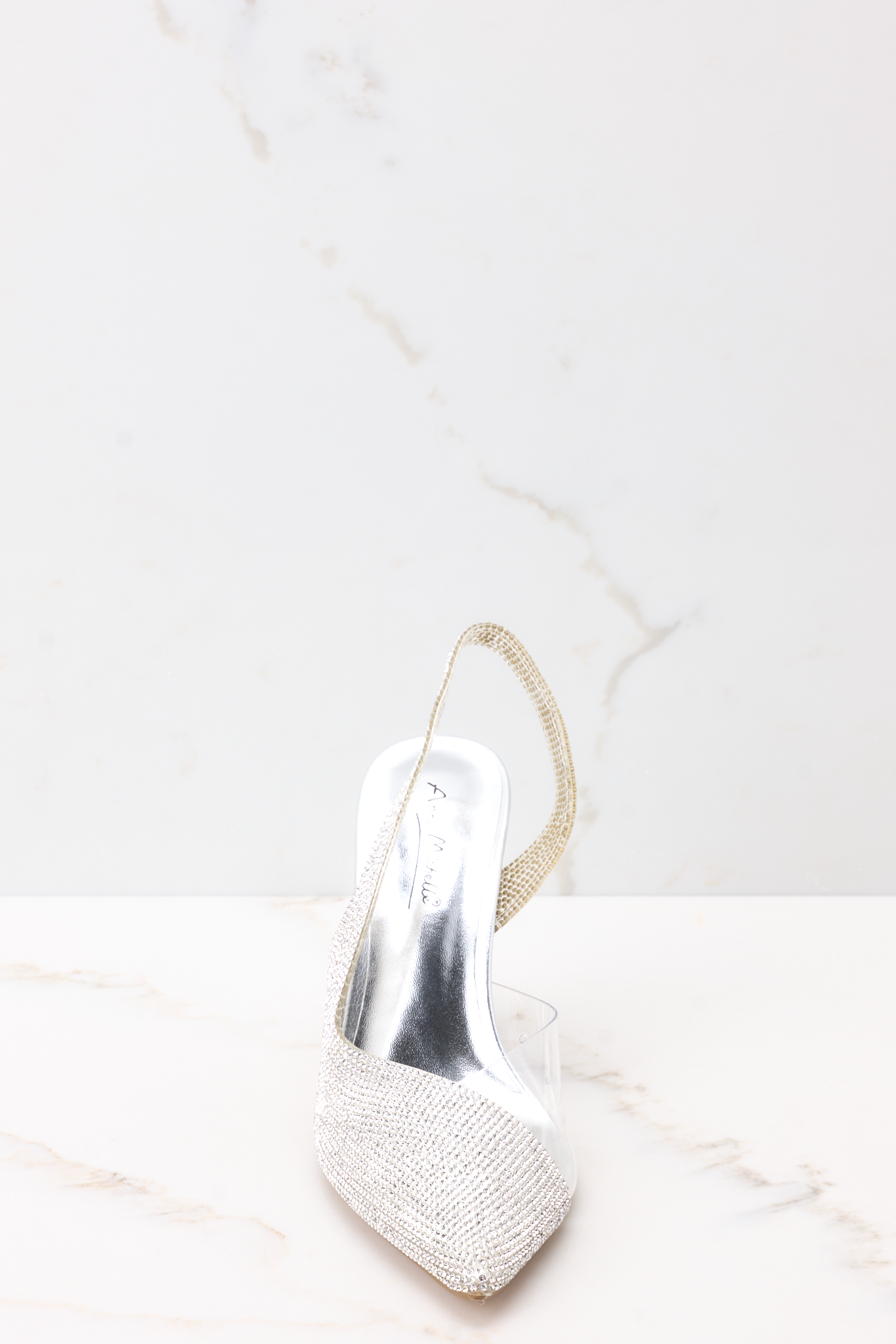 Front view of these heels that feature a pointed toe, rhinestone embellishments, a clear strap on the inside, and a non-adjustable back strap.