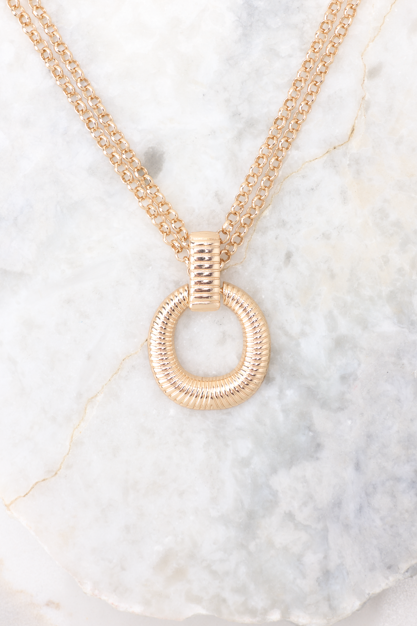 Here is a close-up of a round, gold pendant with groove detailing. 