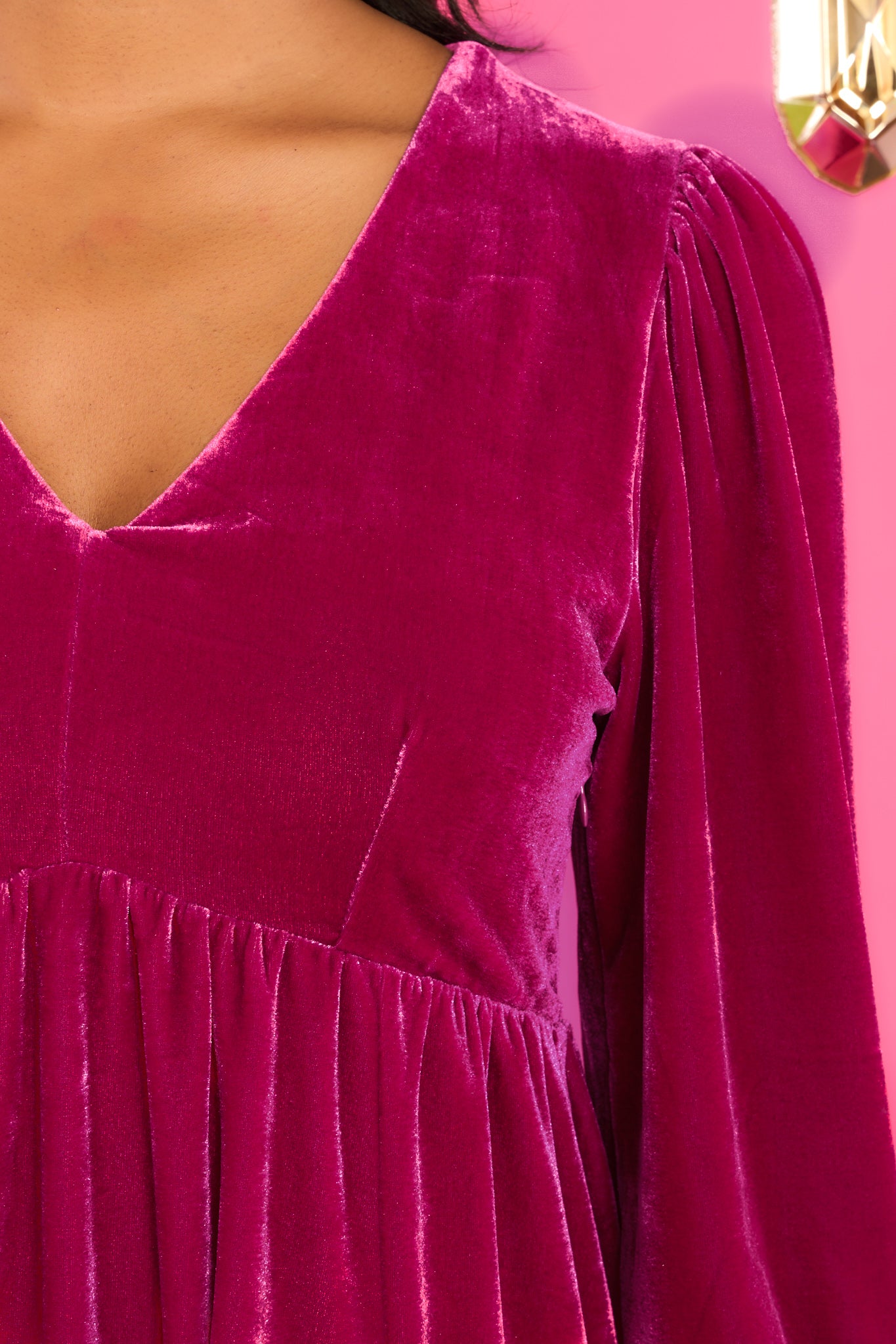 Close up view of this dress that features a v-neckline, long sleeves with elastic cuffs, and a functional side zipper. 