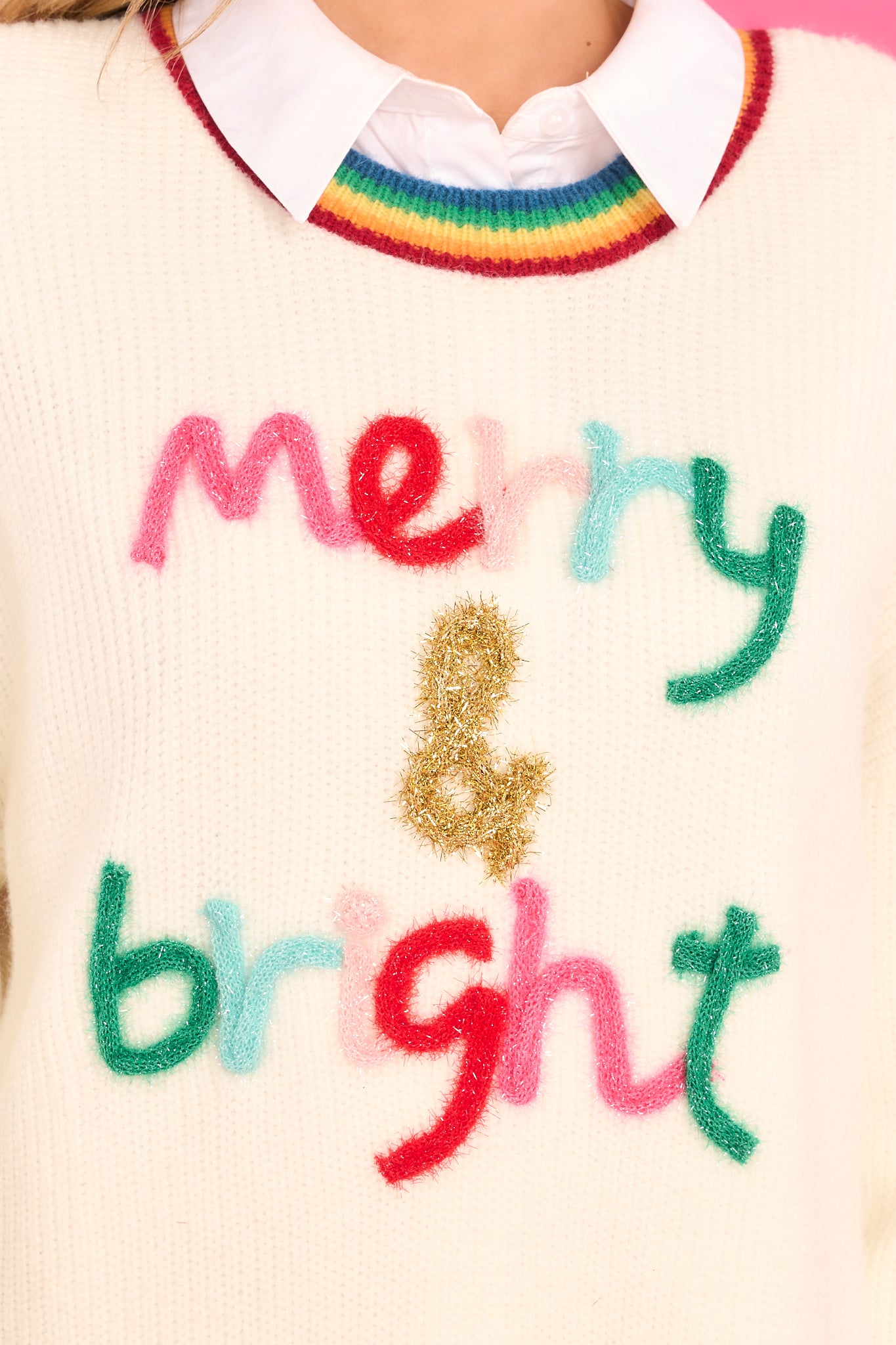 Close up view of this sweater that features a shimmery script design that says "Merry & bright."