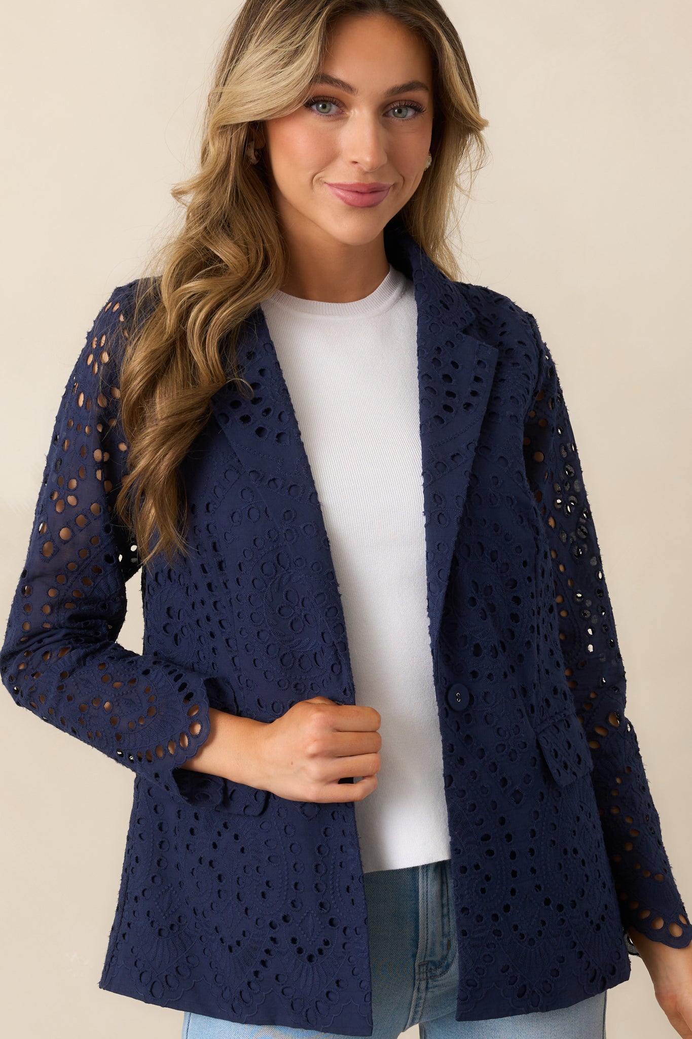 A classic navy blazer with a notch lapel neckline, featuring an elegant eyelet embroidered overlay and a tailored fit