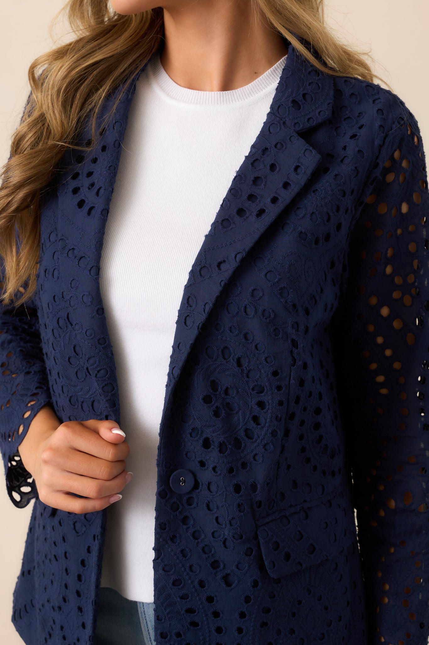 A detailed view of the eyelet embroidery and button closure, showcasing the intricate craftsmanship of this navy blazer.