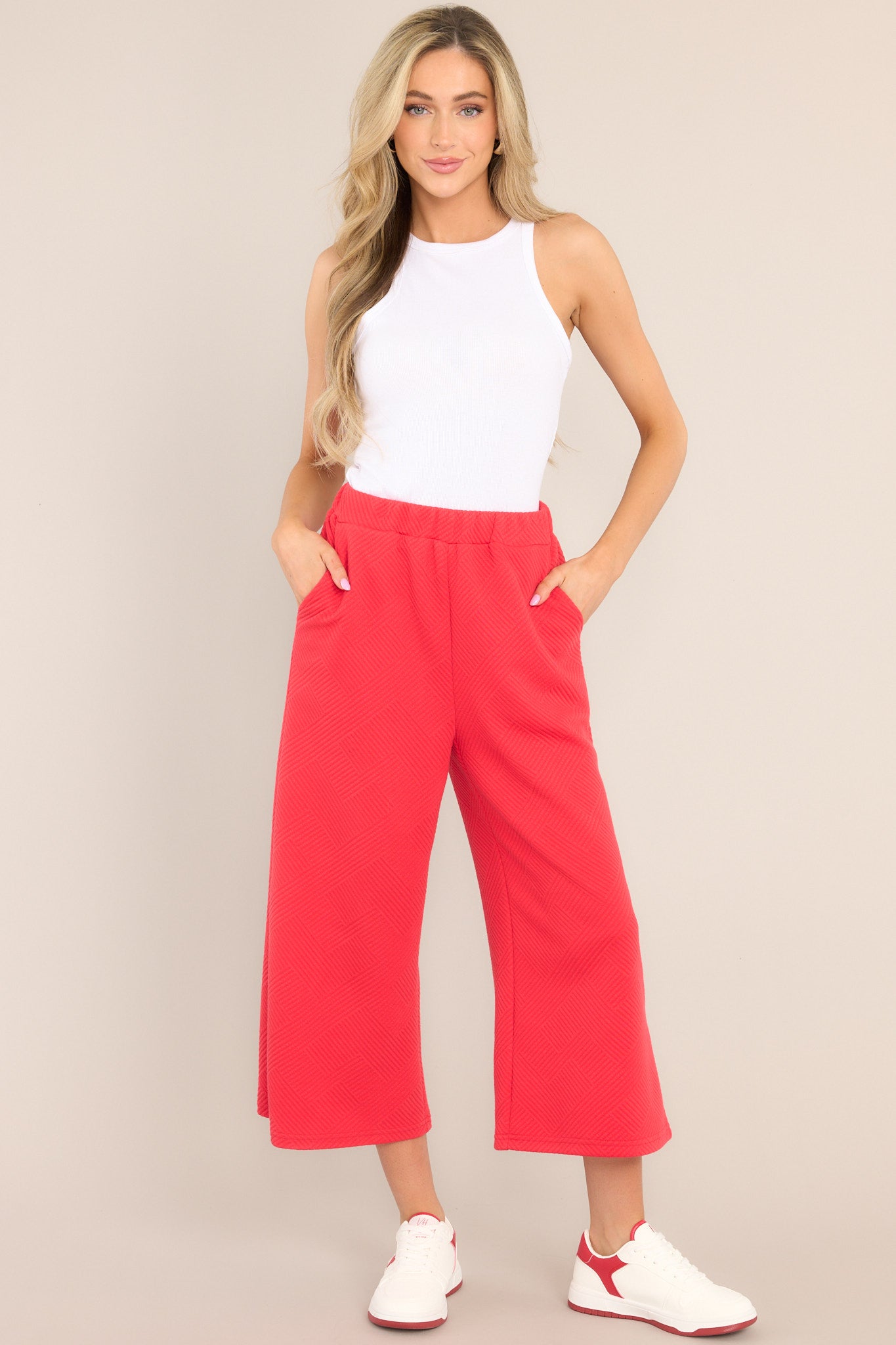 Full body view of these pants that feature a high waisted design, an elastic waistband, functional hip pockets, a textured crisscross design, and a wide leg.