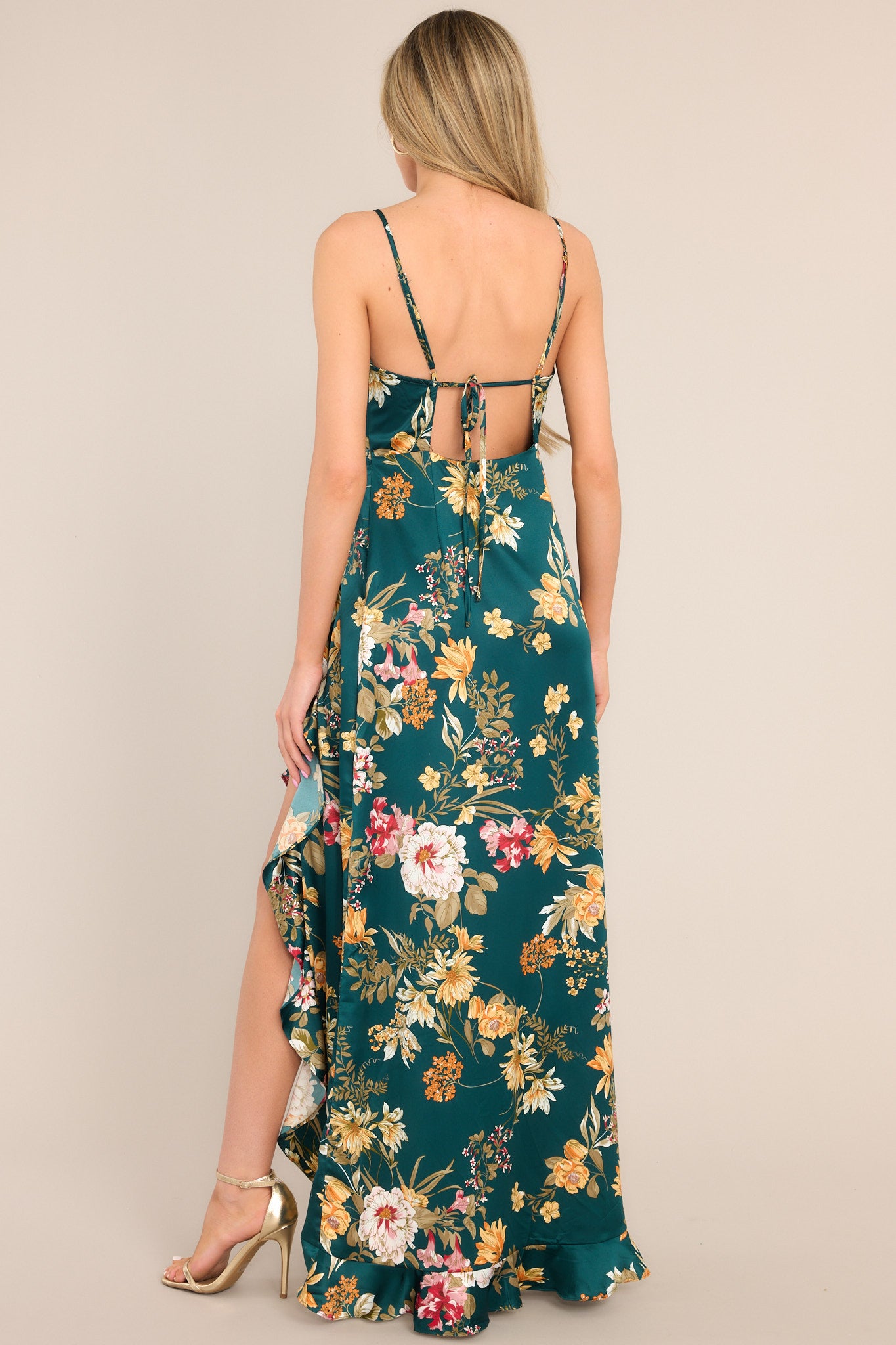 Back view of this emerald floral dress that features a v-neckline, adjustable straps, an open back, a functional side zipper, a faux wrap design, and a high slit.