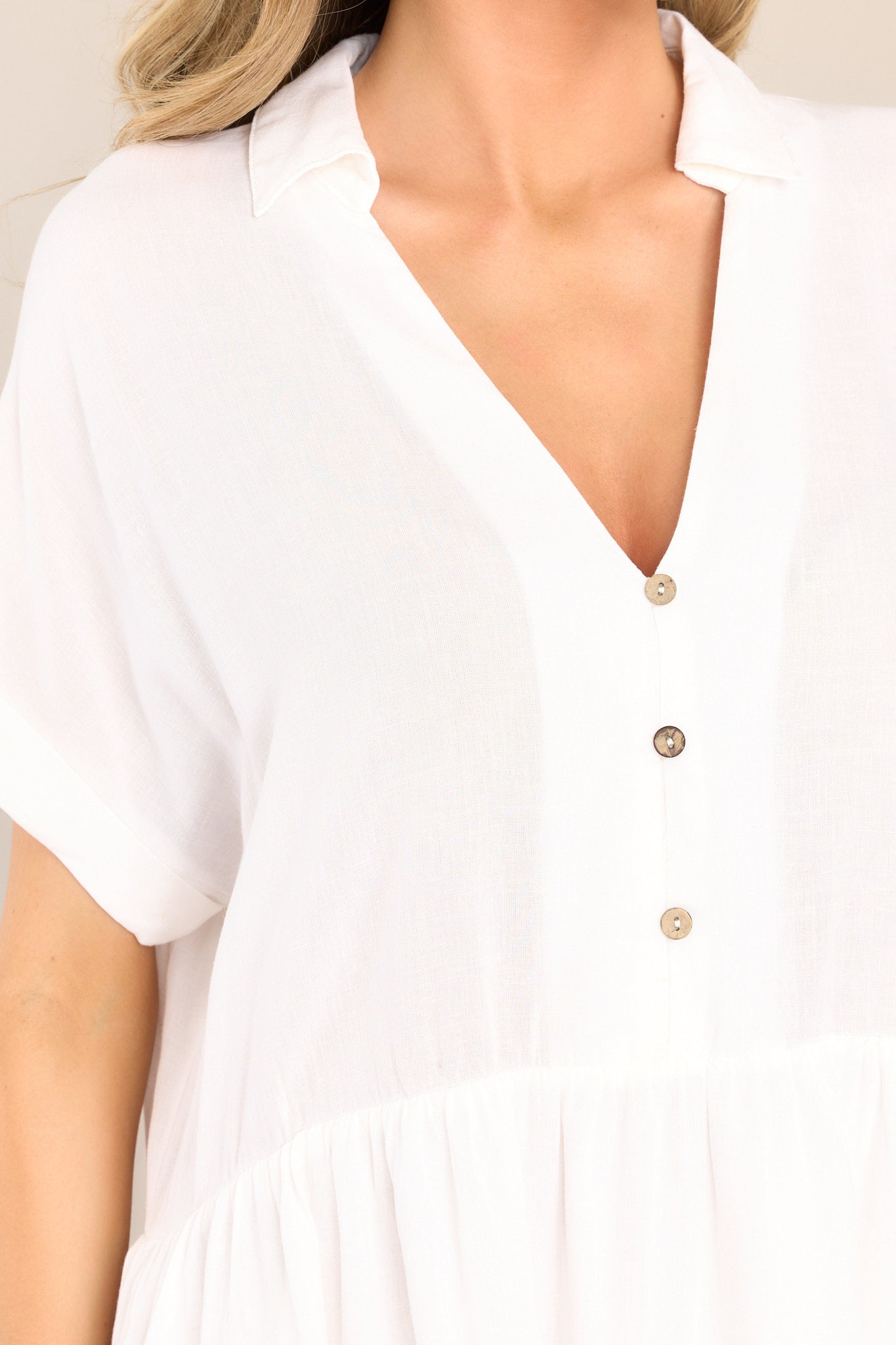 Close up of the V neckline and buttons down the front of the bust on this white mini dress.