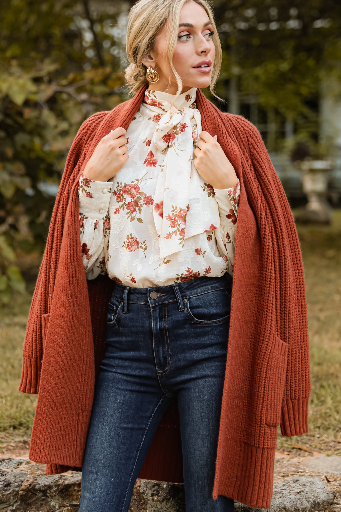 This brown cardigan features a folded neckline that extends down the front, functional pockets, and a knit texture throughout.