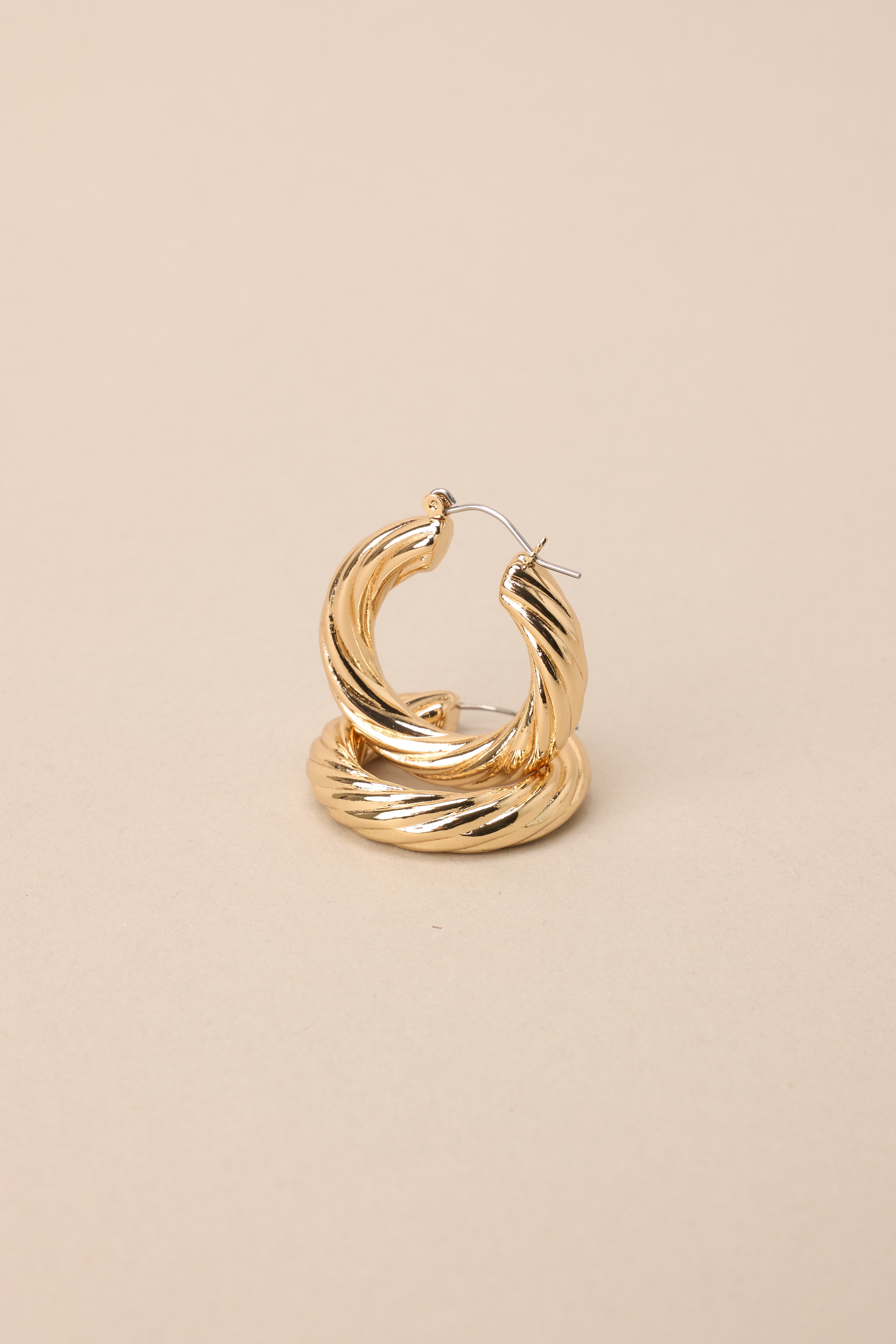 Close up view of these gold hoops that feature gold hardware, a twisted design, and a lever back closure.