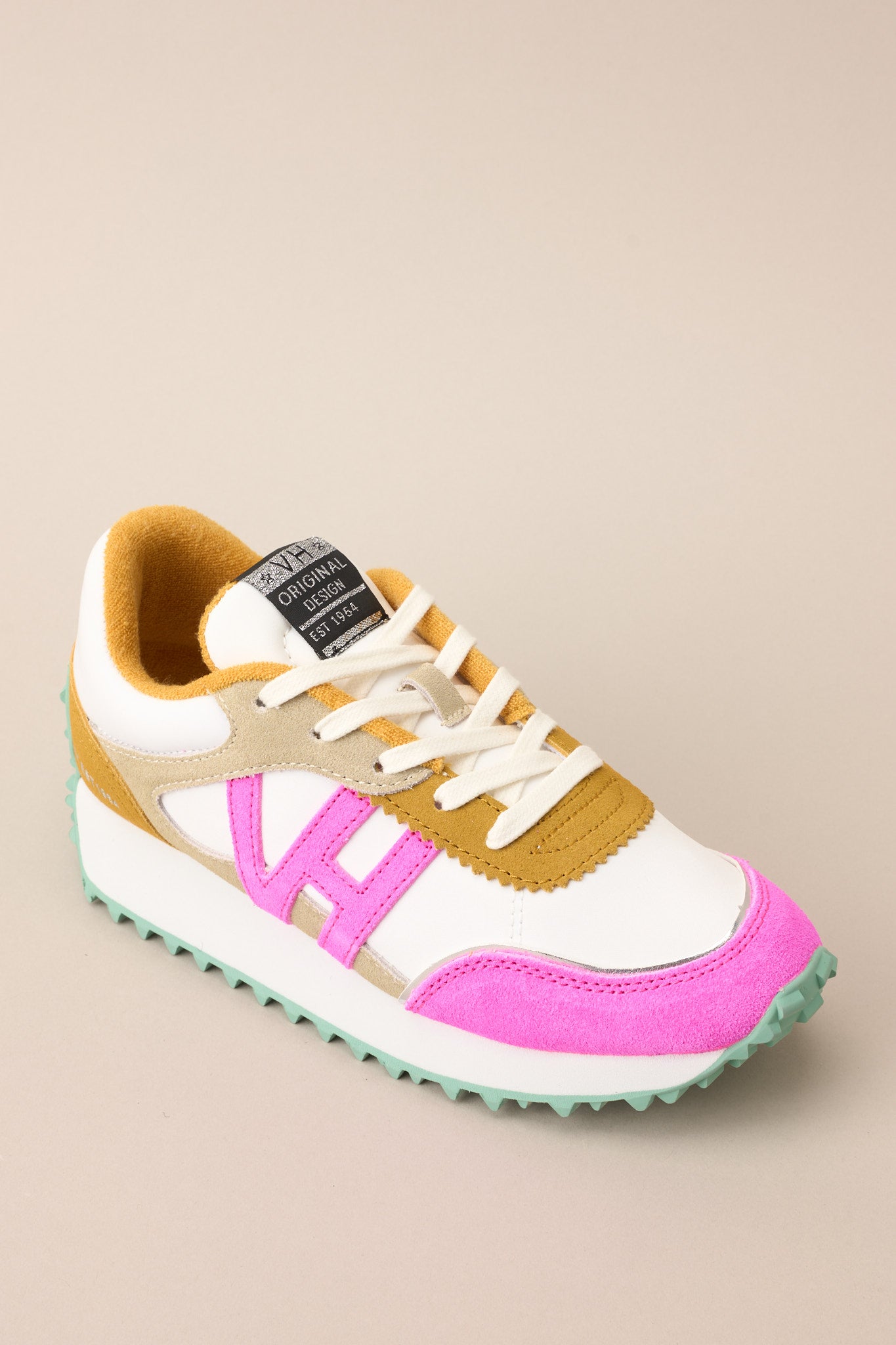 Angled top view of these sneakers that feature a rounded toe, functional laces, pops of color, a slight platform, and a heavily textured sole.