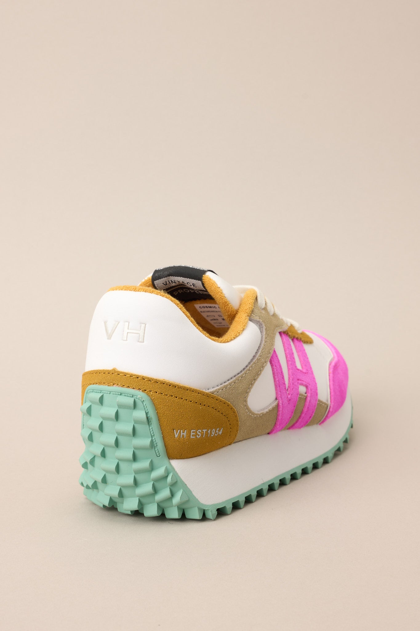 Close up back view of these sneakers that feature a rounded toe, functional laces, pops of color, a slight platform, and a heavily textured sole.