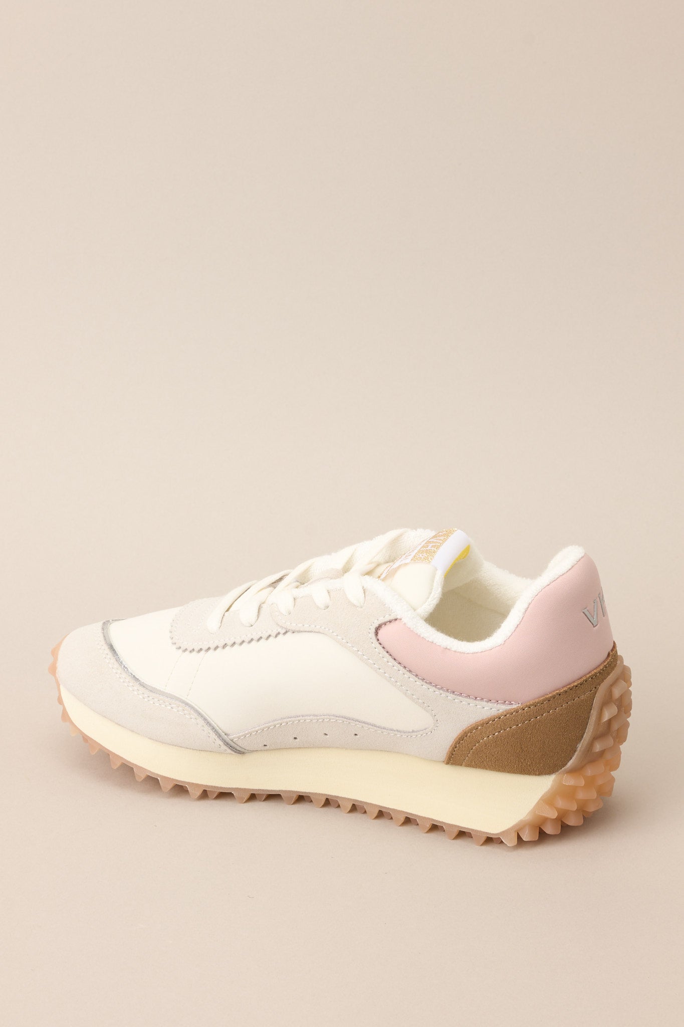 Inner-side view of these sneakers that feature a rounded toe, functional laces, subtle pops of color, a slight platform, and a heavily textured sole.