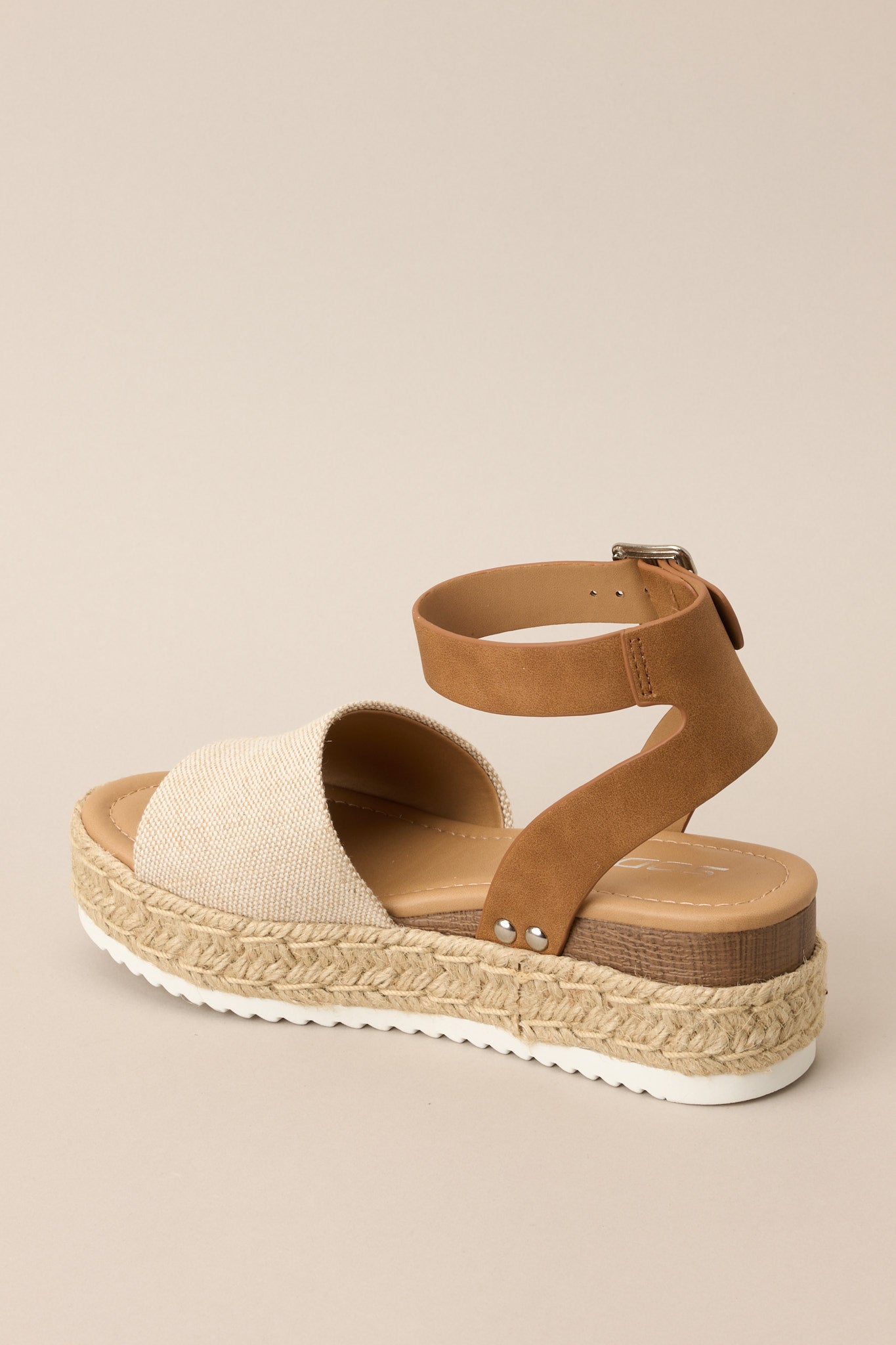 Inner-side view of these sandals that feature a rounded toe, silver hardware, a textured strap over the top of the foot, a contrasting strap around the heel and ankle, and a buckle closure.