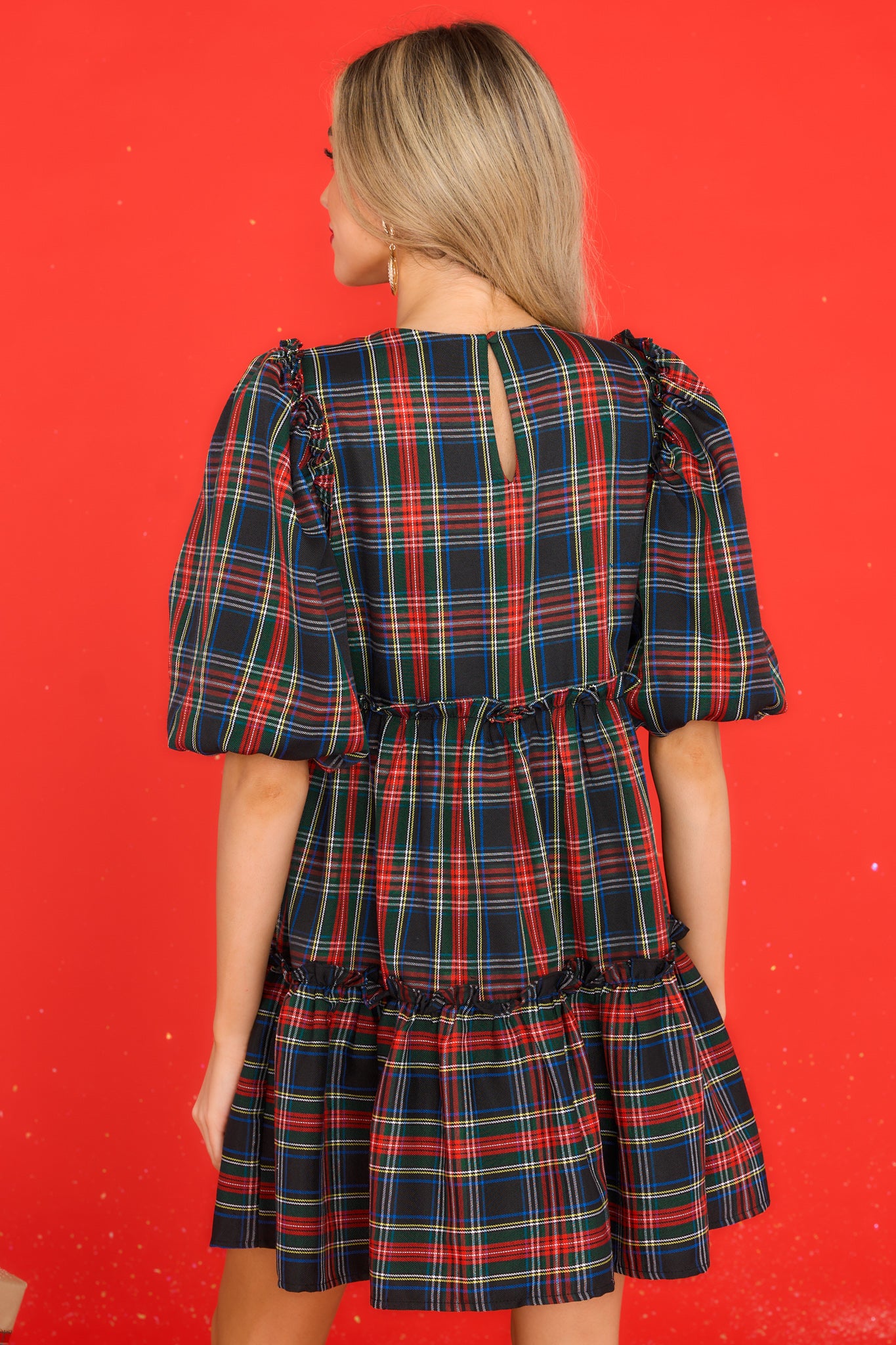 Back view of this dress that features a round neckline, puff sleeves with elastic cuffs, a keyhole cutout in the back with a button closure, and small ruffled detailing throughout.