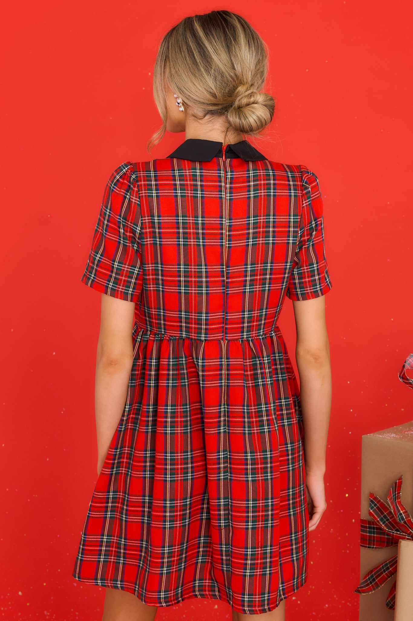 Back view of this dress that features a collar neckline with a sequin bow detail, a back zipper closure, pockets, and a pleated skirt.