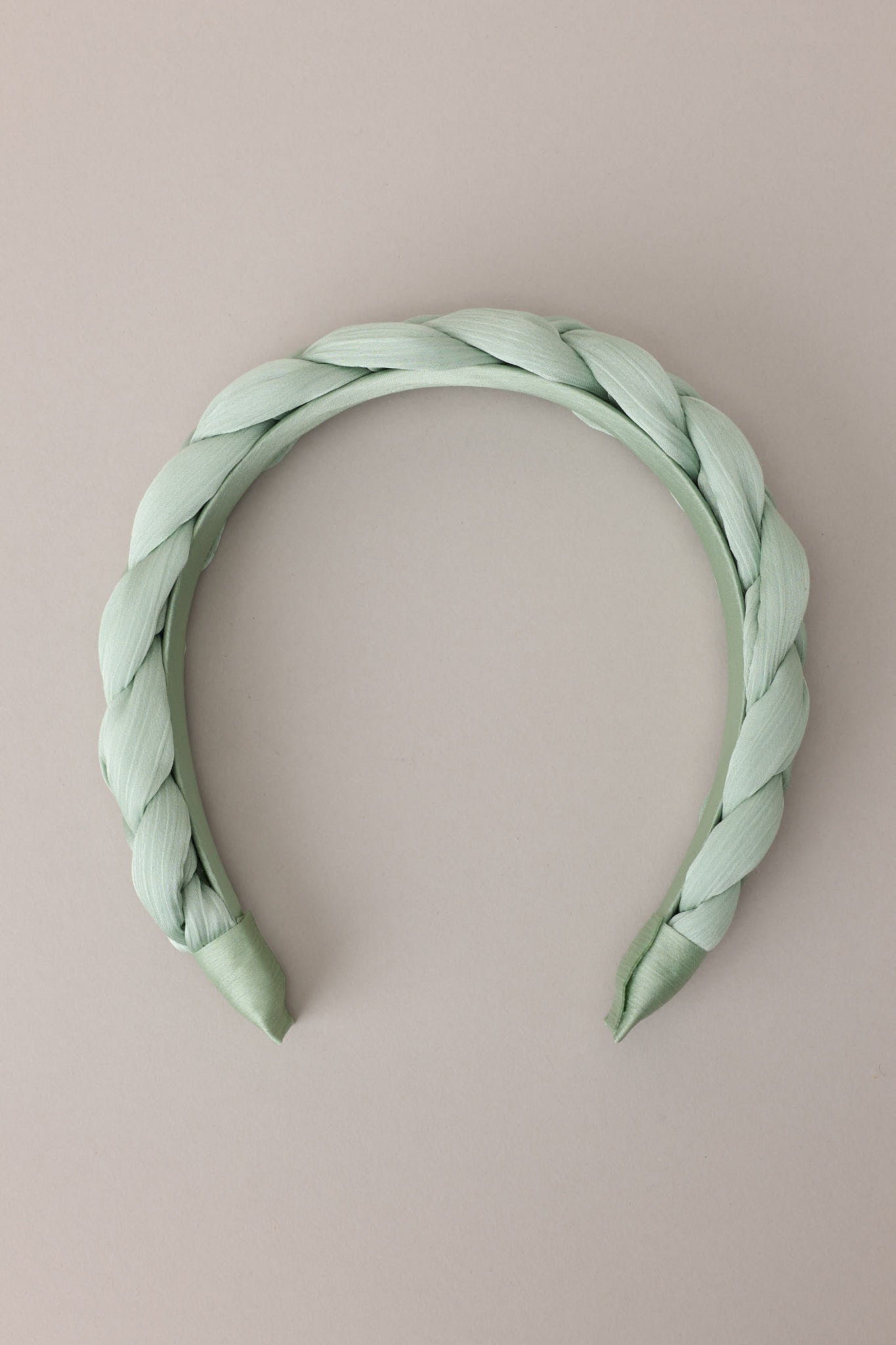 Flat front view of this headband that features a thick, soft material, and a braided texture.&nbsp;