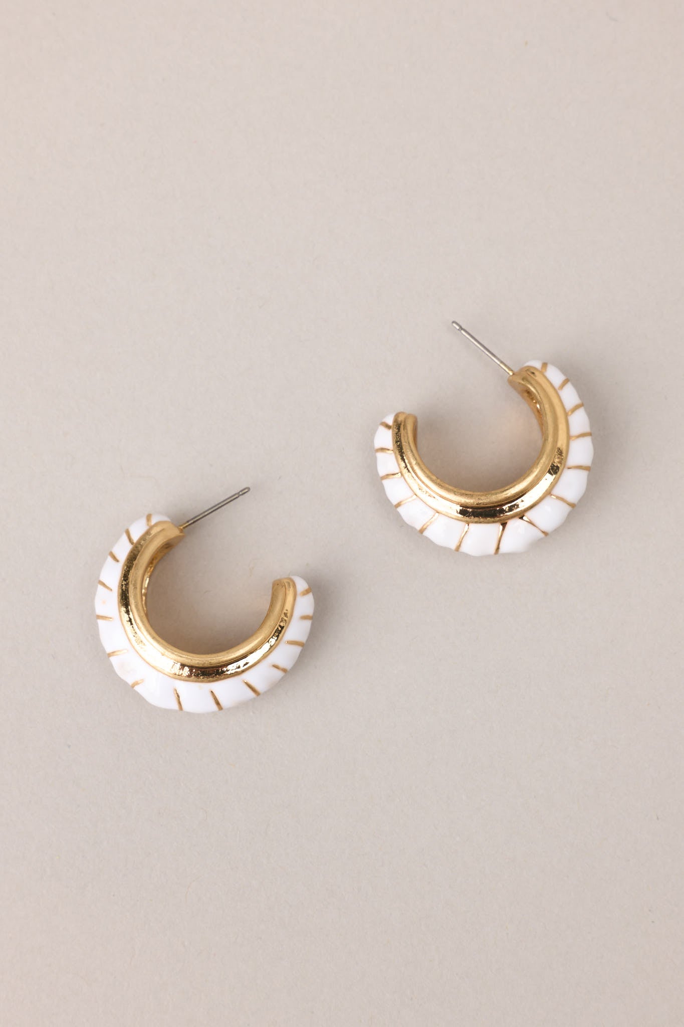 Overview of these gold earrings with white detailing, secure post backings.