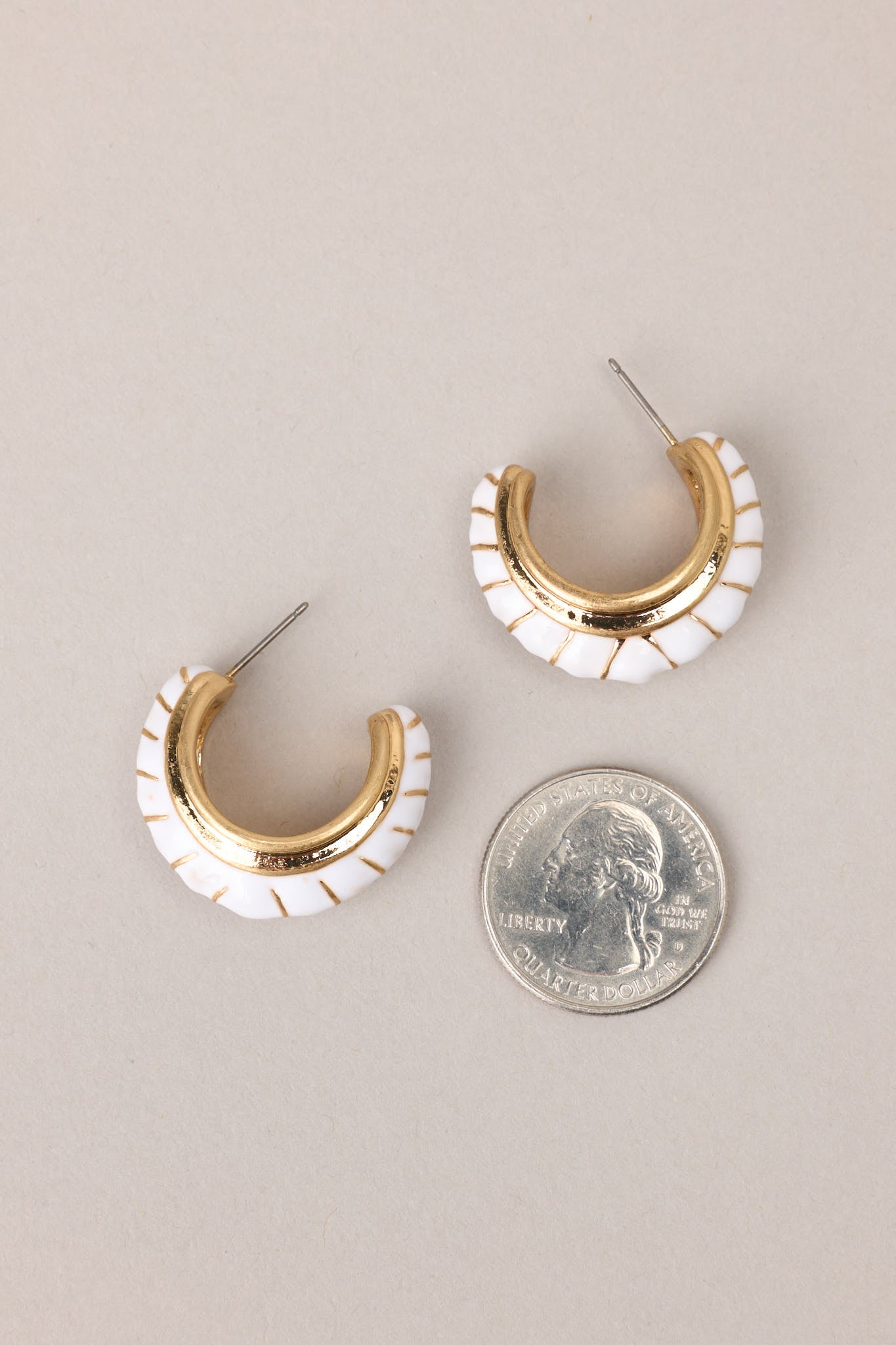 Size comparison of these gold earrings with white detailing, secure post backings.