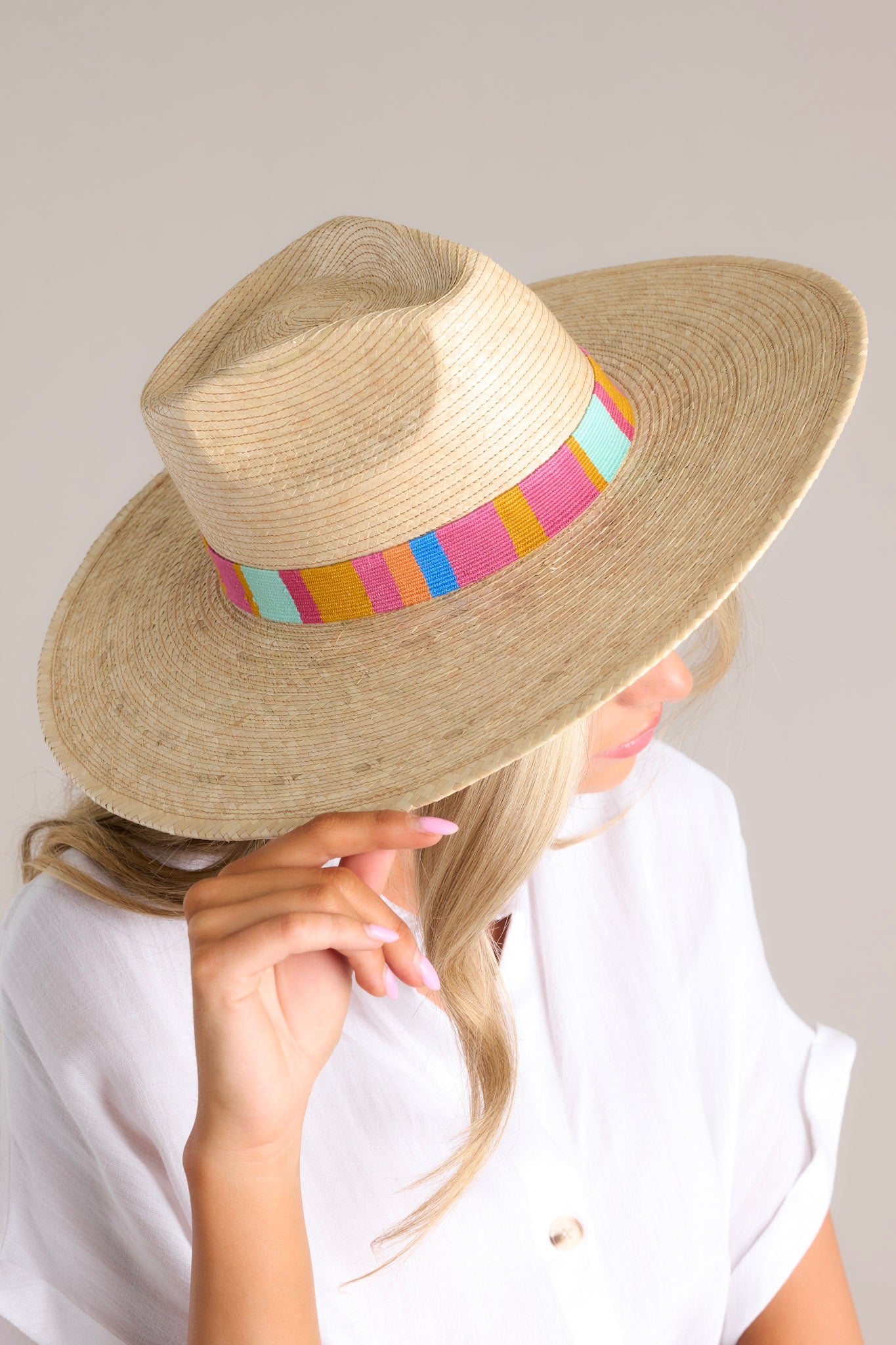 Side view of this hat that features a multicolor cotton woven band, and is handmade with palm fronds.