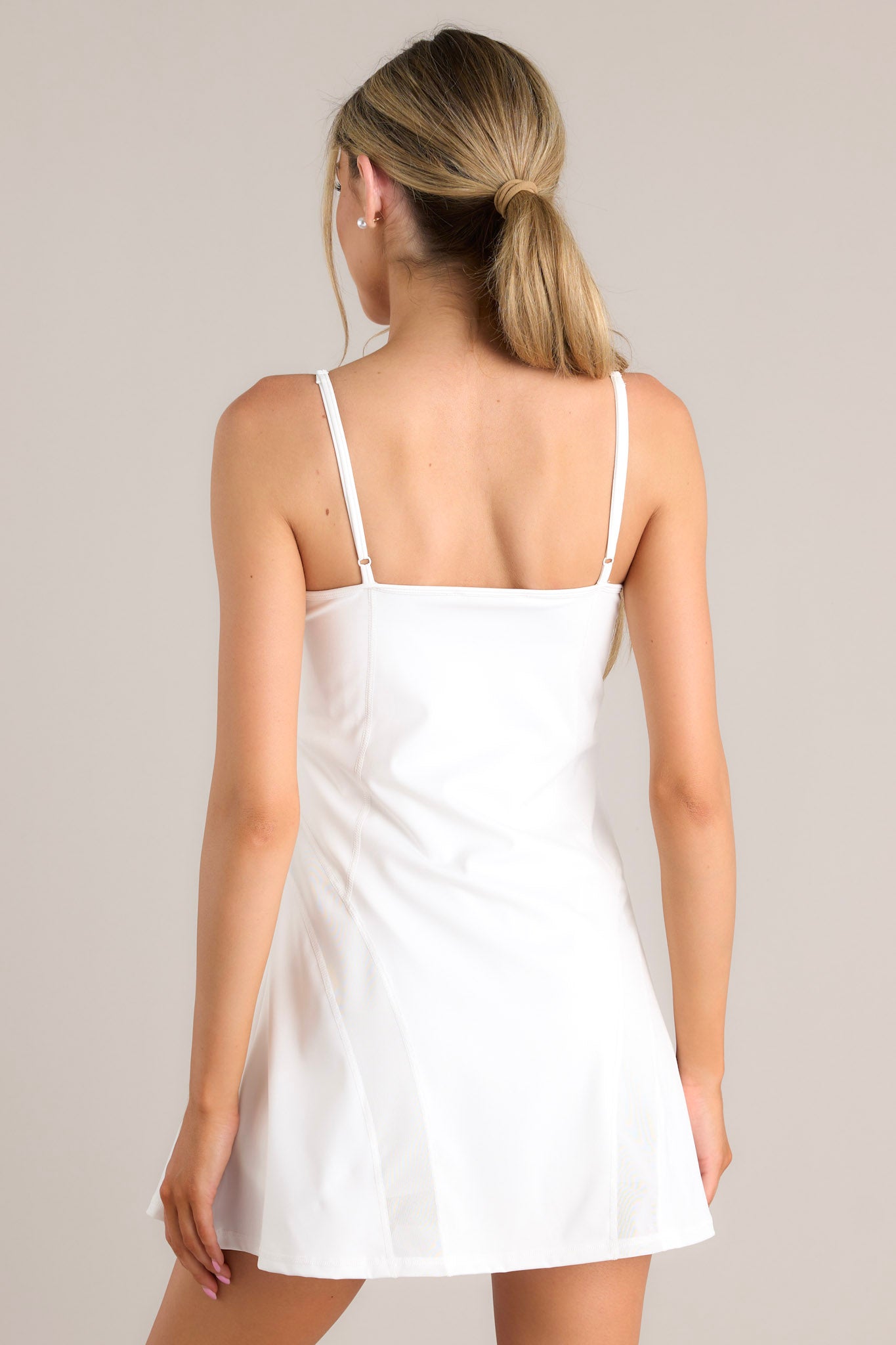 Back view of this dress that features a rounded neckline, thin adjustable straps, a built-in shelf bra, built-in shorts with functional pockets, and semi transparent detailing.