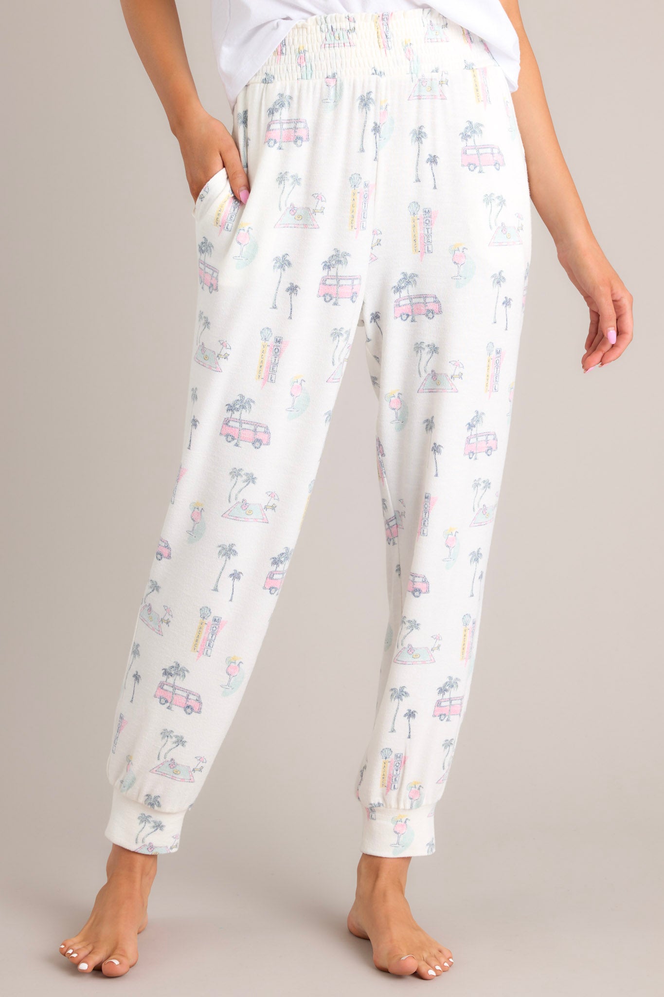 A close up view of the front of these pants that feature a high waisted design, a fully smocked waistband, functional hip pockets, and cuffed ankles.