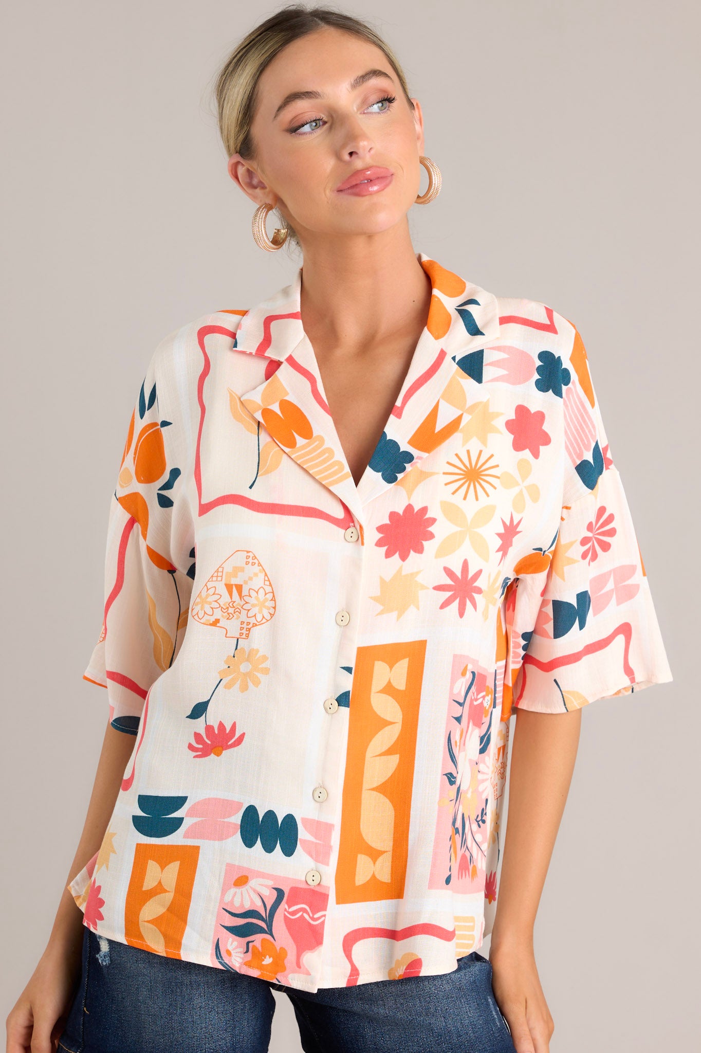 Front body view of this apricot multi print top that features functional buttons down the front, a citrus and floral print design, a collared neckline, and lightweight fabric.