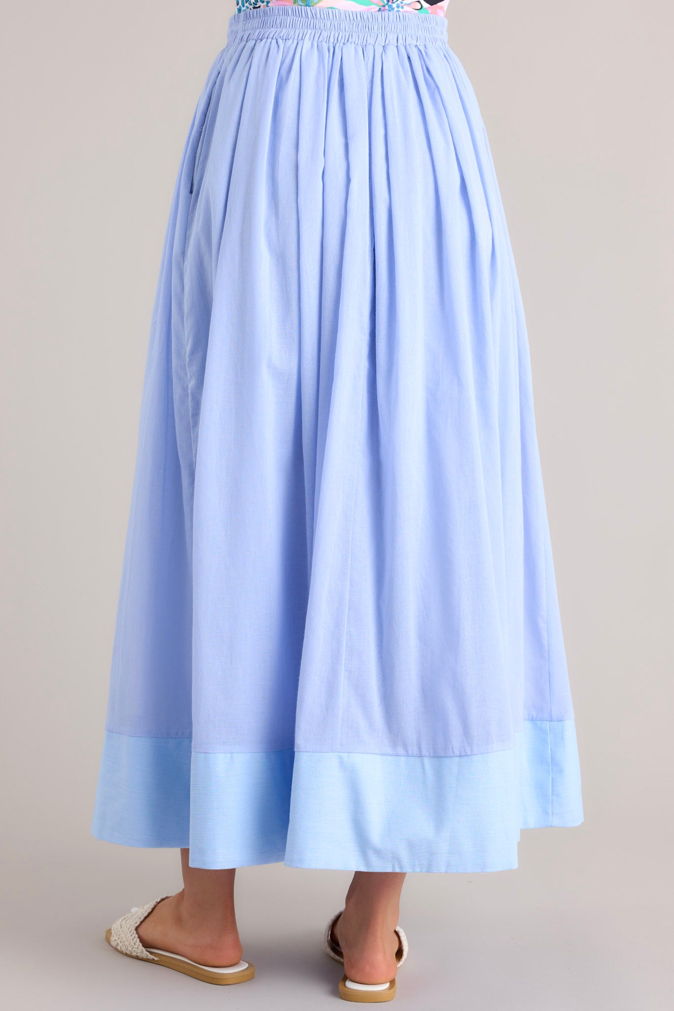 Back view of this skirt that features a high waisted design, an elastic waistband, a self-tie drawstring, functional pockets, flowing fabric, and a thick hemline.