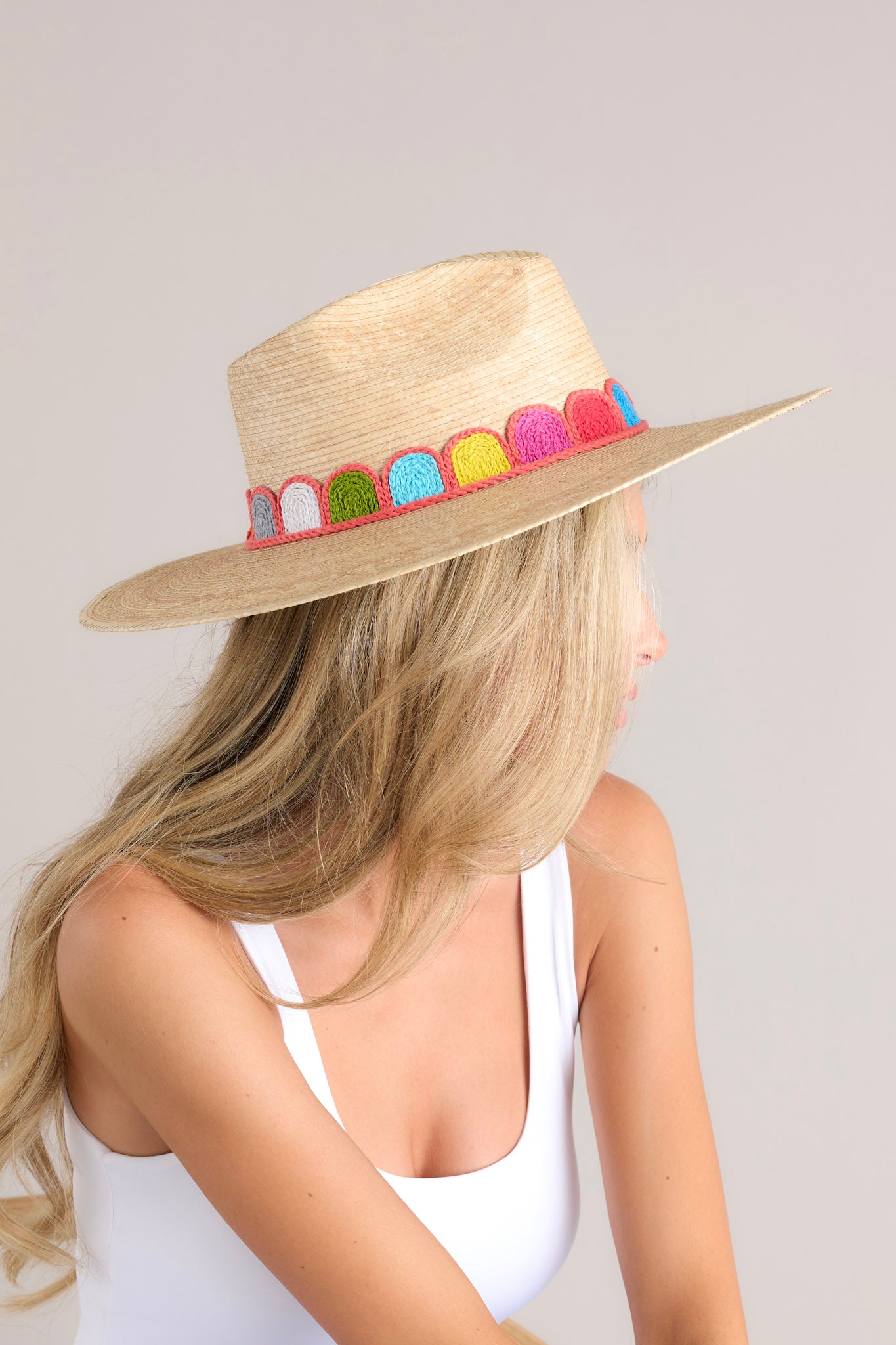 Side view of this hat that features a woven striped band, and is handmade with palm fronds.