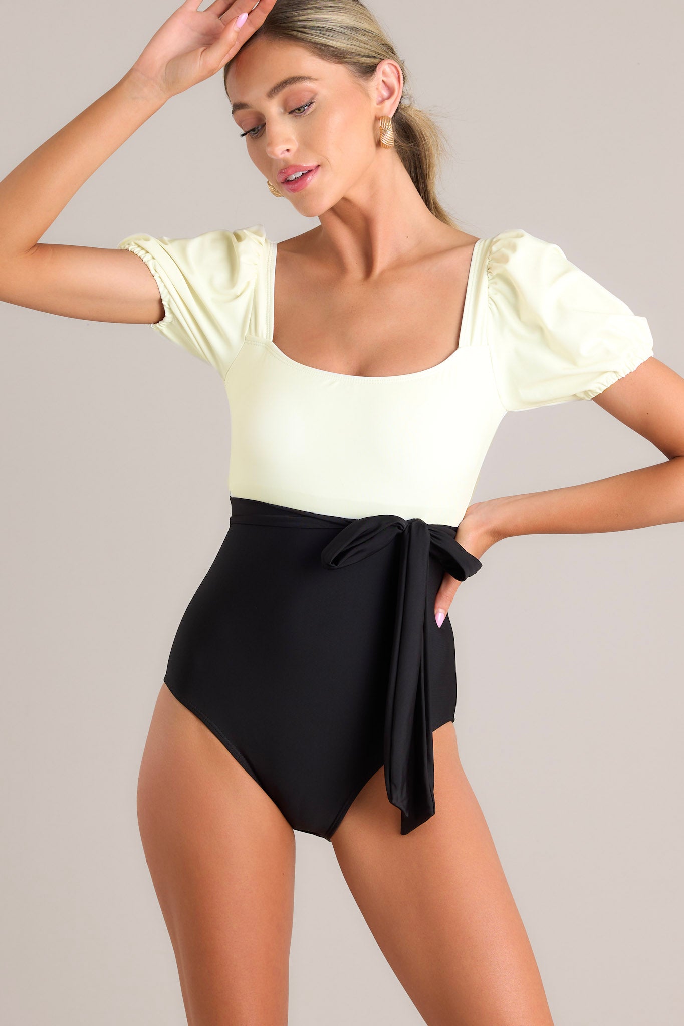 Front view of  this one piece that features a square neckline, removable padding, a color block design, a self-tie waist, elastic cuffed short sleeves, and a full coverage backside.