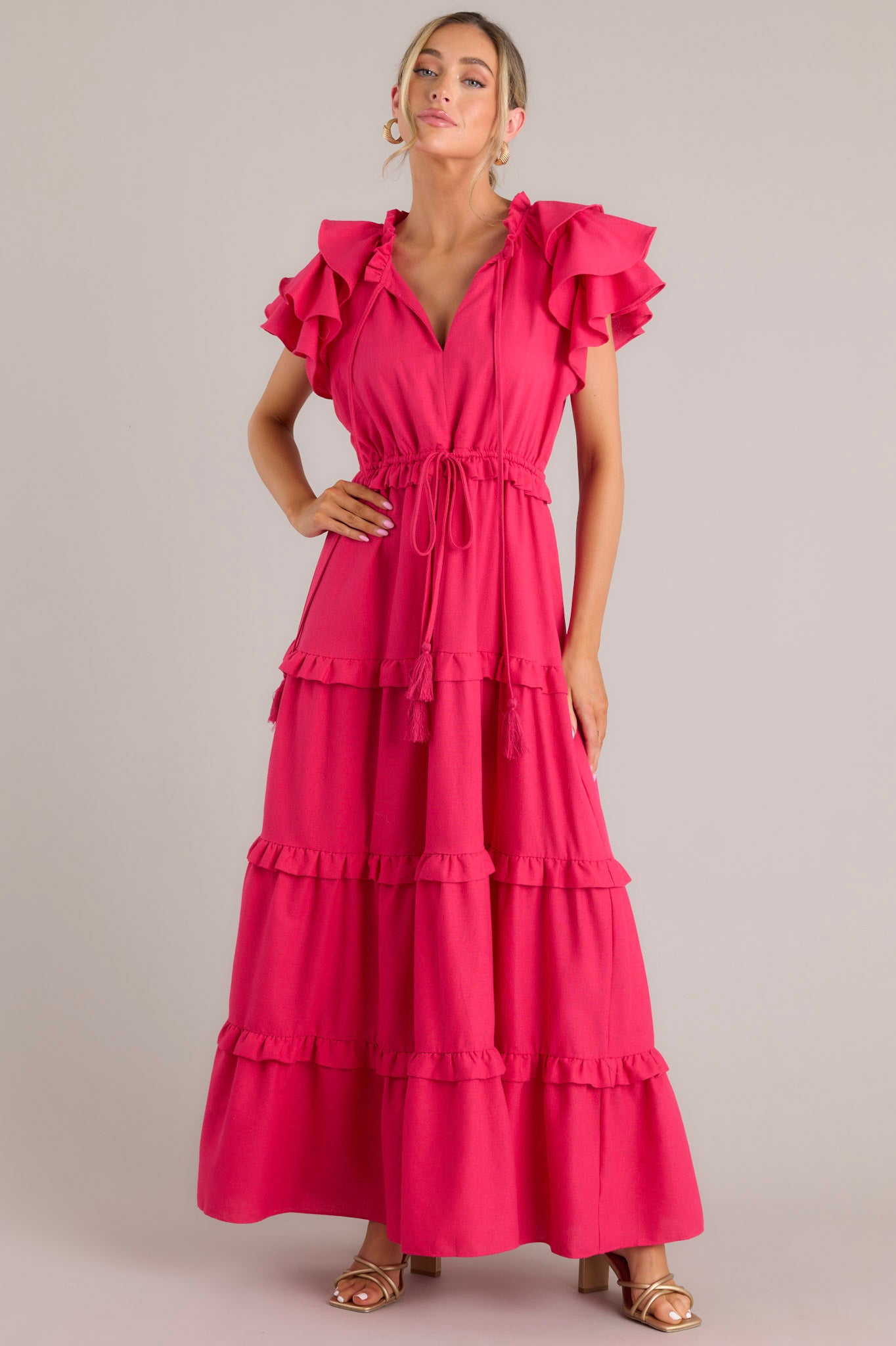 Front view of this dress that features a v-neckline with a self-tie closure, ruffled flutter sleeves, a drawstring waistband, and a long, flowy skirt.