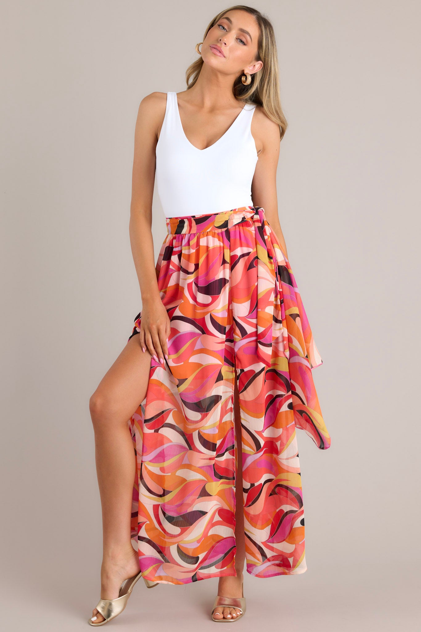 Full body view of this skirt that features a high-waist design, a self-tie wrap around belt, an elastic section at the back of the waistband, and slits up the leg on either side of the skirt.