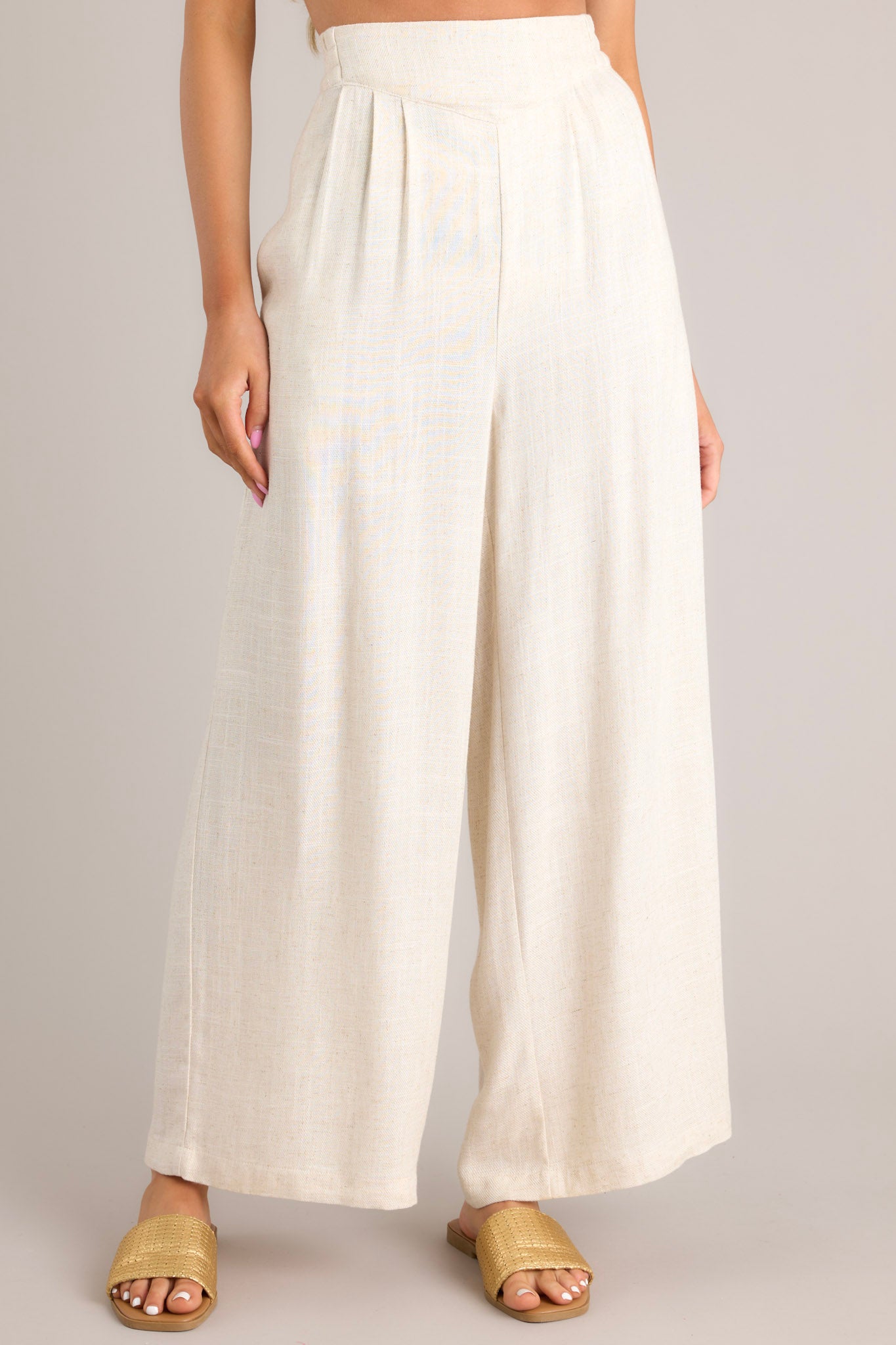 Front view of these pants that feature a high waisted design, an elastic insert in the back, functional hip pockets, a lightweight fabric, and a wide leg design.