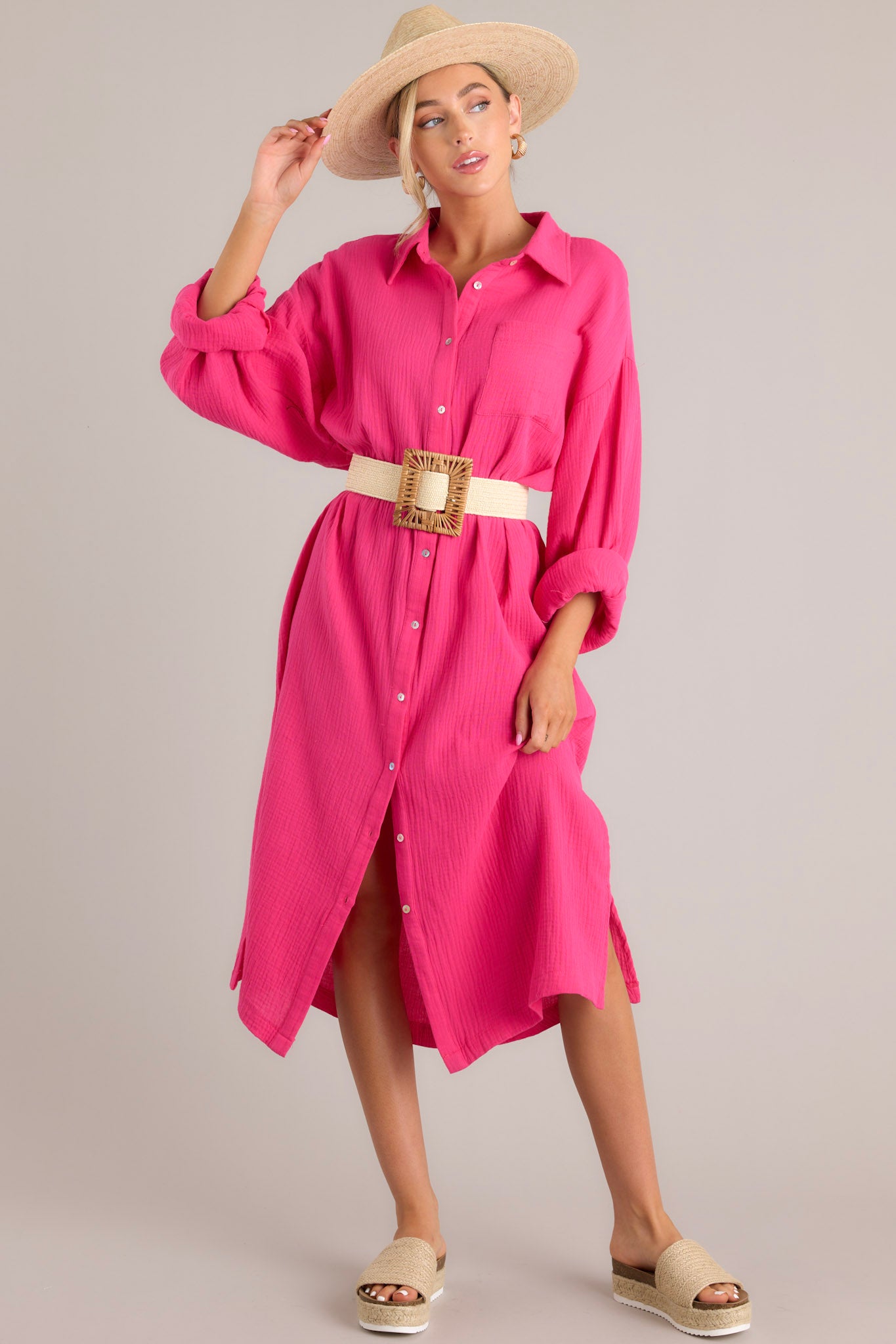 Front view of this dress that features a collared neckline, functional buttons down the front, a front pocket on the left side of the bust, long sleeves with a cuff secured by a functional button, and two slits up the bottom hemline ending just below the knee.