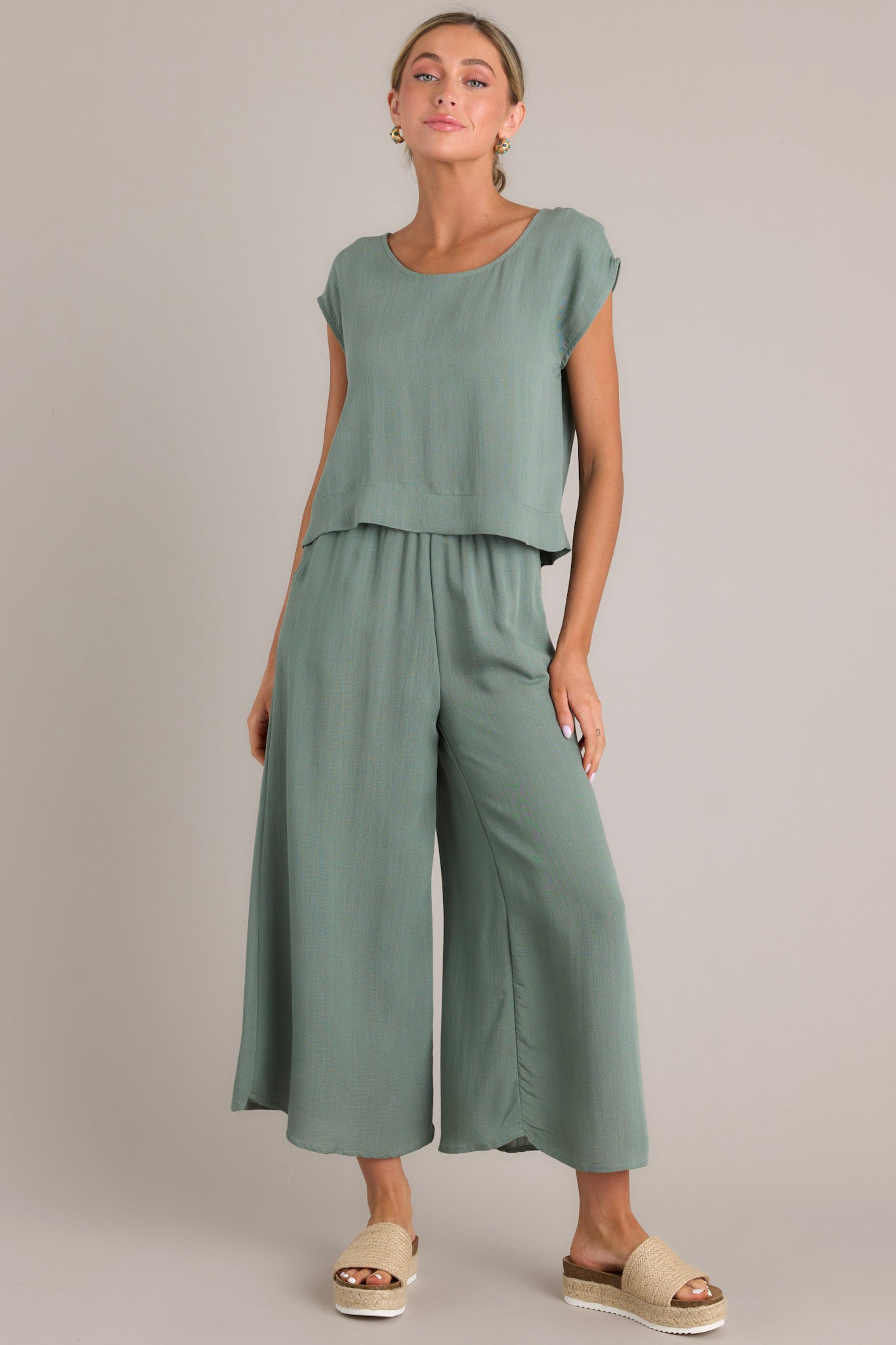 Full body view of these pants that feature a high waisted design, an elastic waistband, functional hip pockets, a wide leg design, and a slightly cropped length.