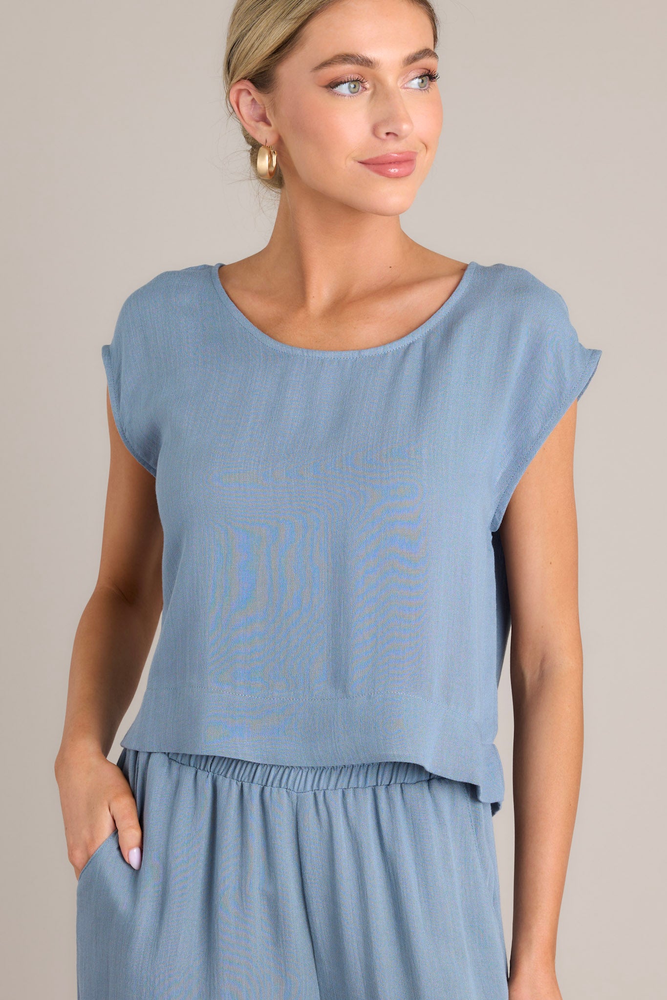 This top features a cap sleeve design, a crew neckline, slightly cropped length, and breezy lightweight fabric.