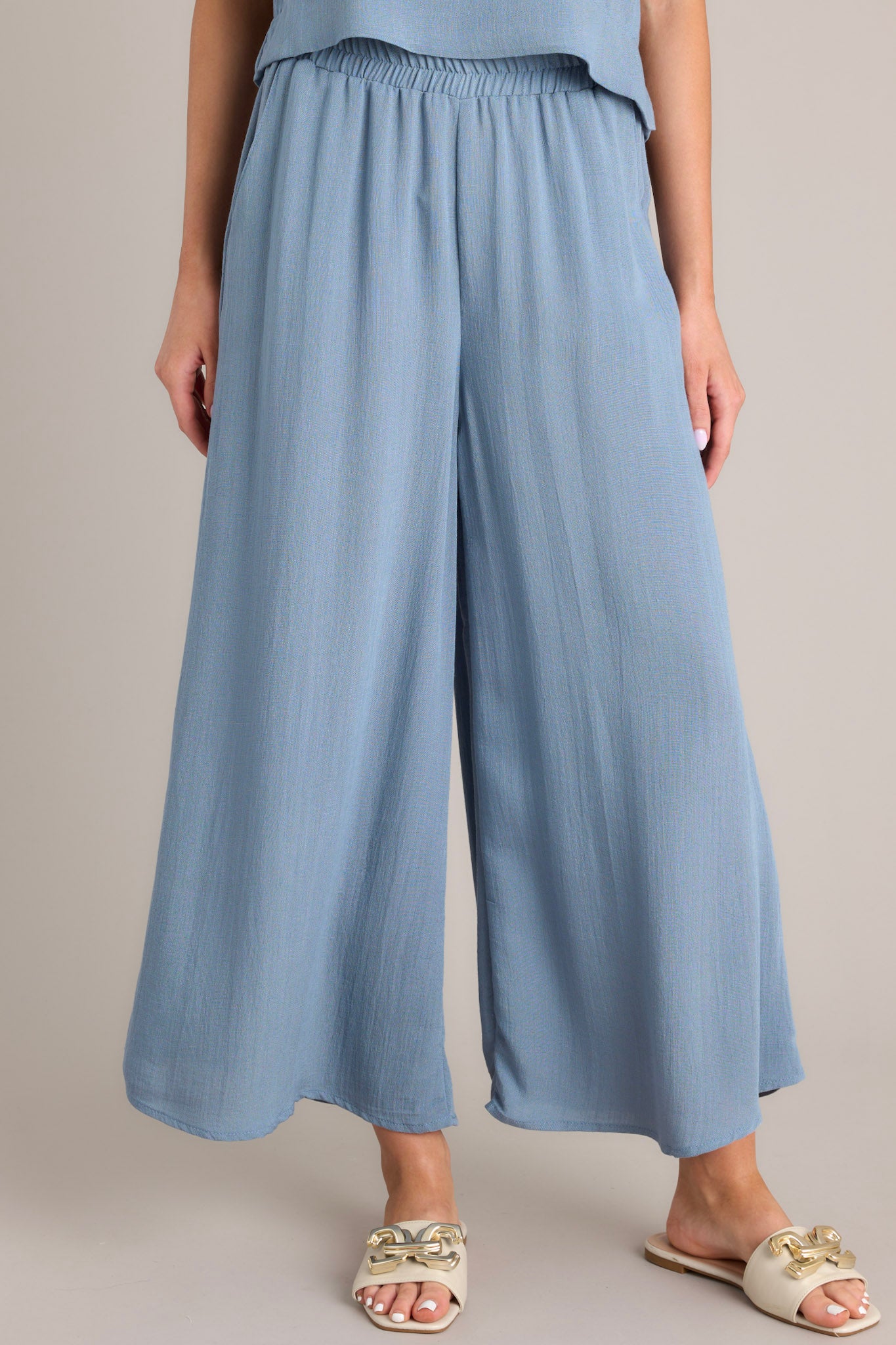 Front view of these pants that feature an elastic waistband, functional pockets, a cropped length, and a lightweight fabric.