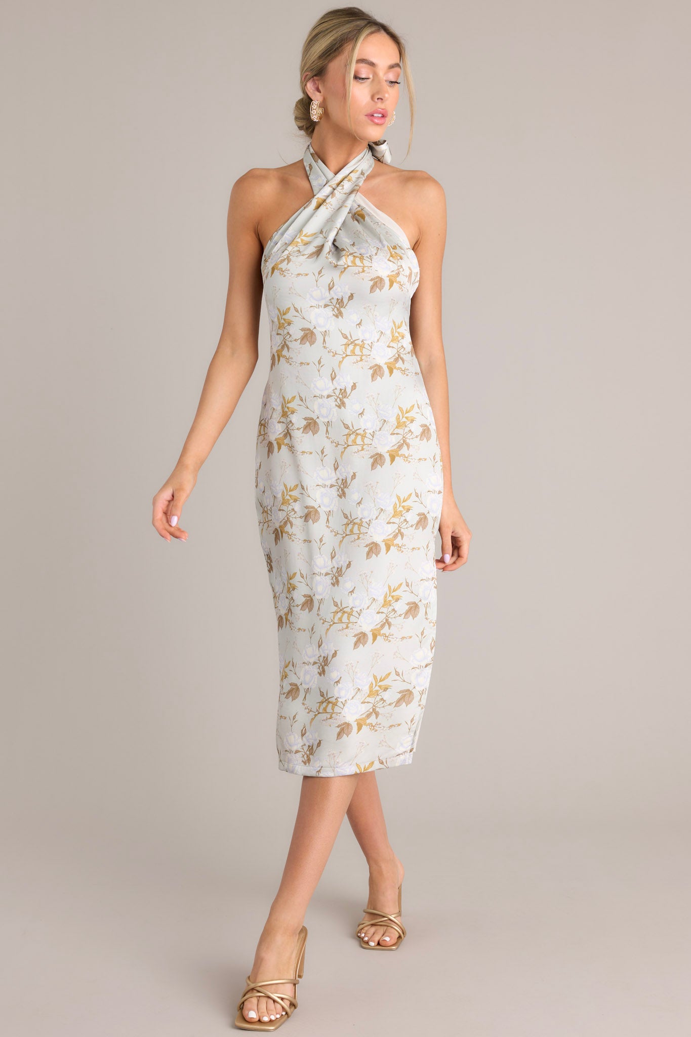 Angled full body view of this light sage midi dress that features a self-tie halter neckline, an open back, a discrete back zipper, a soft material, and a side slit