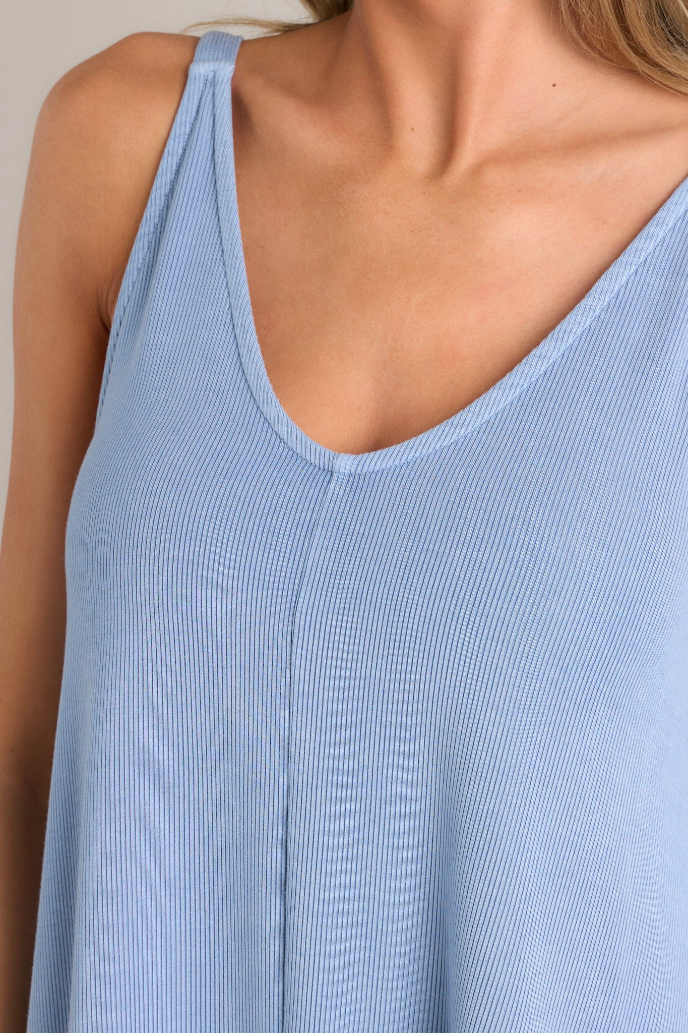 Close up view of this blue ribbed dress that features a v-neckline, a seam down the front and back and, a soft & lightweight material.