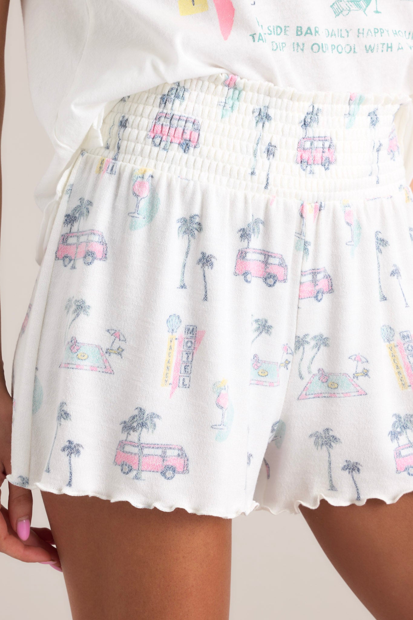 Close up view of these shorts that feature a high waisted design, a fully smocked waistband, a super soft &amp; lightweight material, a tropical print, and a lettuce trim hemline.