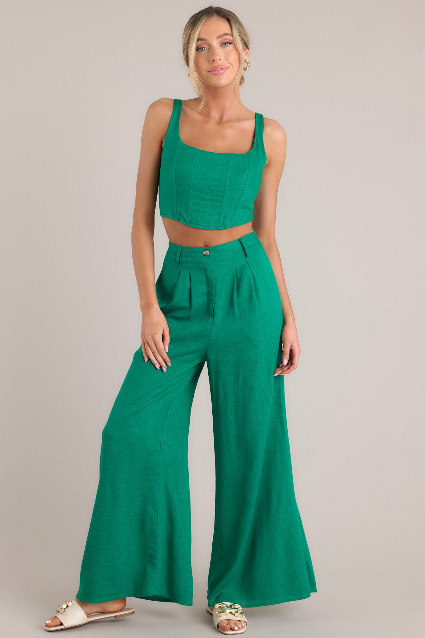 These green pants feature a high waisted design, a functional button and zipper closure, belt loops, an elastic insert at the back of the waist, hip pockets, and a wide leg.