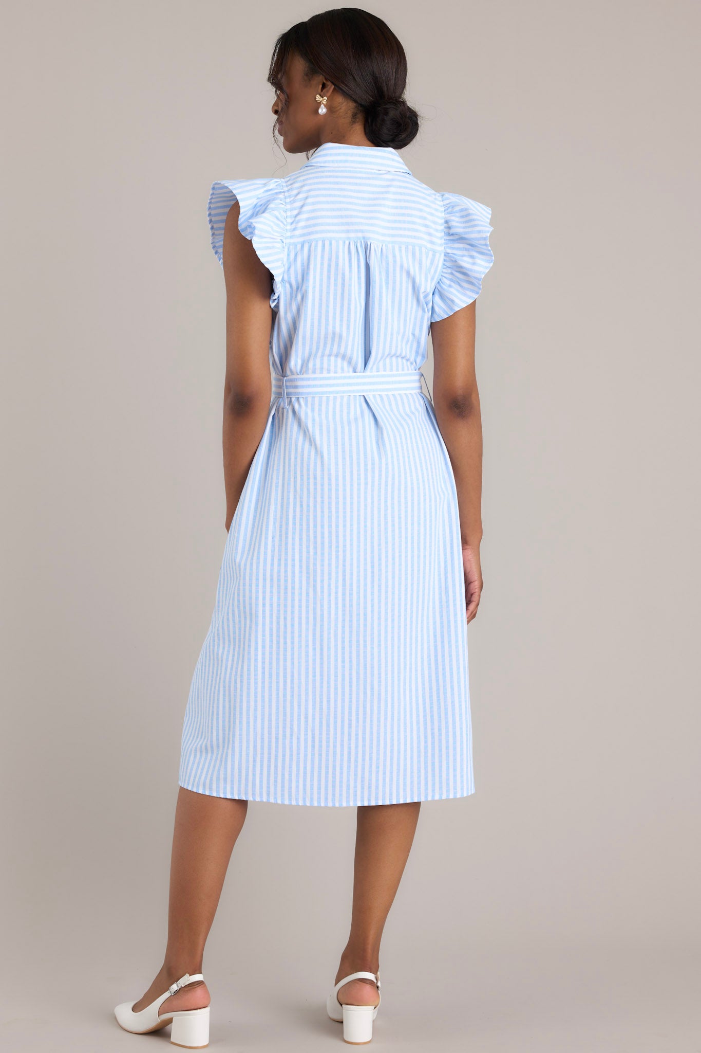 Back view of this dress that features a collared neckline, ruffle sleeves, a full button front, pleated details throughout the front, belt loops, an adjustable belt with a functional buckle, and hip pockets.