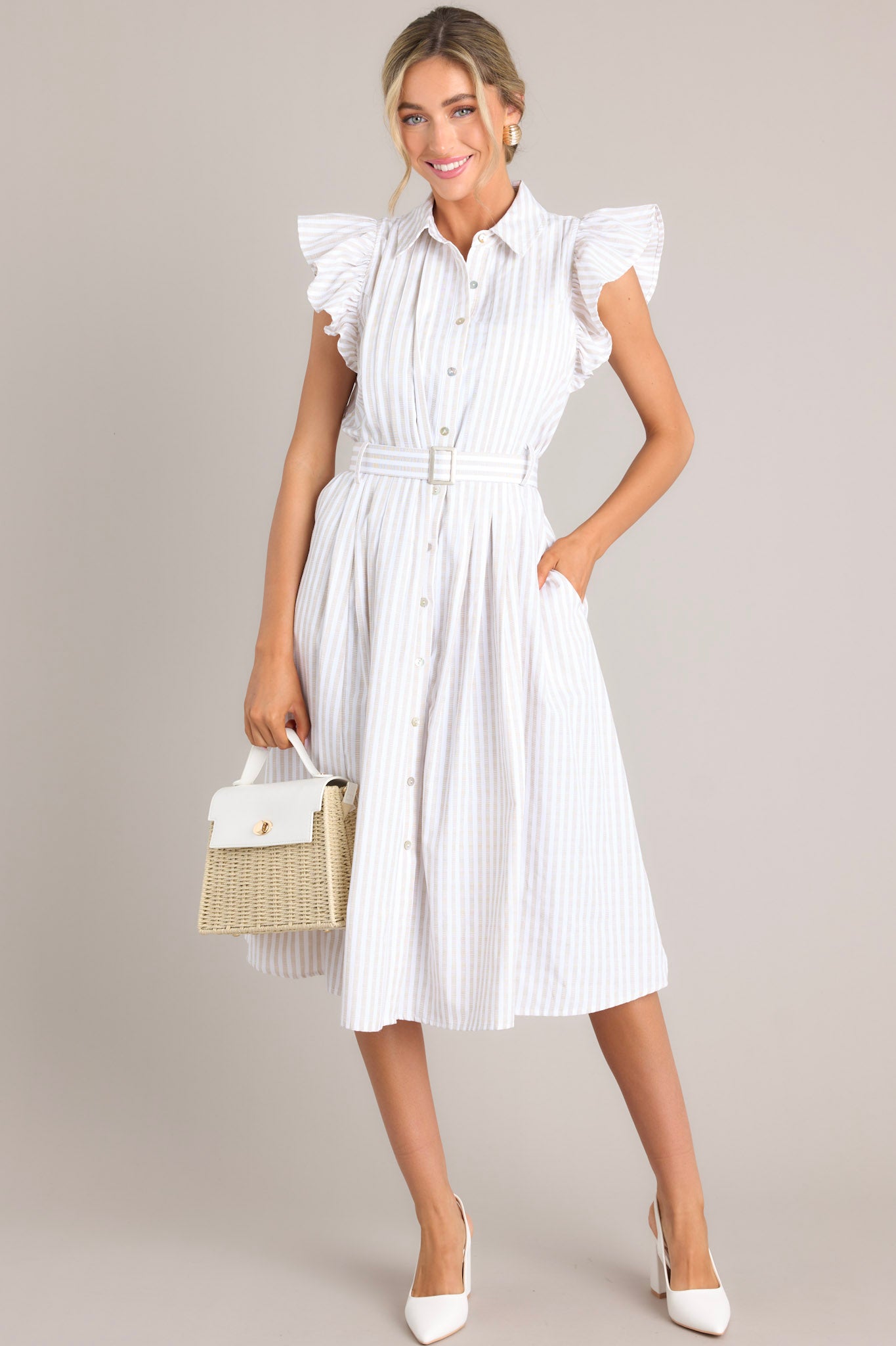 Front view of this dress that features a collared neckline, ruffle sleeves, a full button front, pleated details throughout the front, belt loops, an adjustable belt with a functional buckle, and hip pockets.