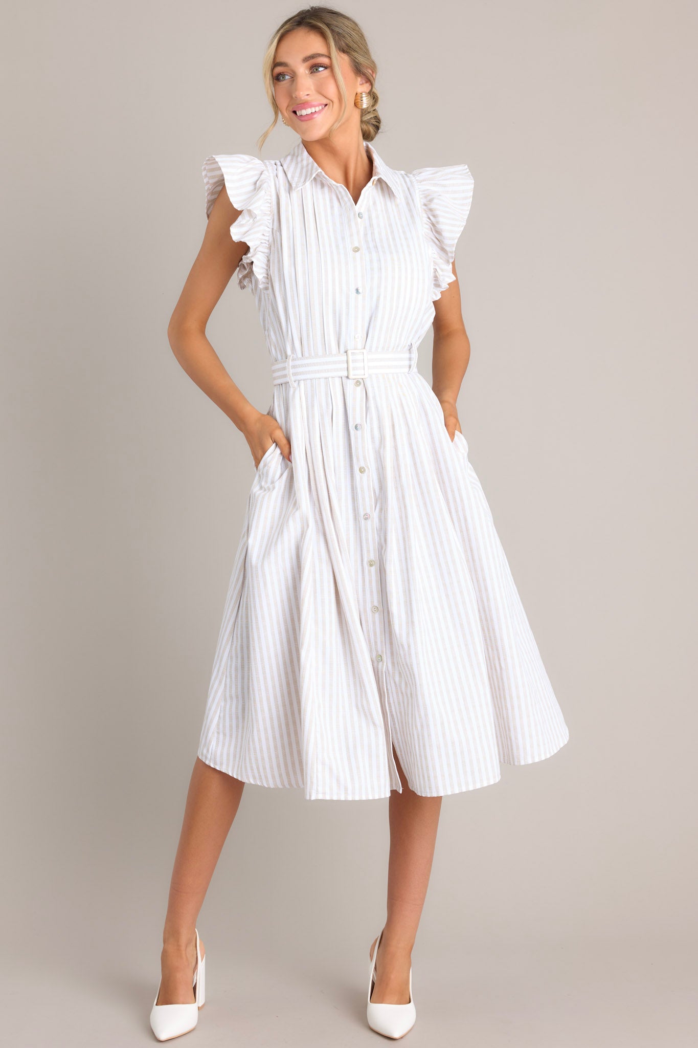 Full body view of this dress that features a collared neckline, ruffle sleeves, a full button front, pleated details throughout the front, belt loops, an adjustable belt with a functional buckle, and hip pockets.