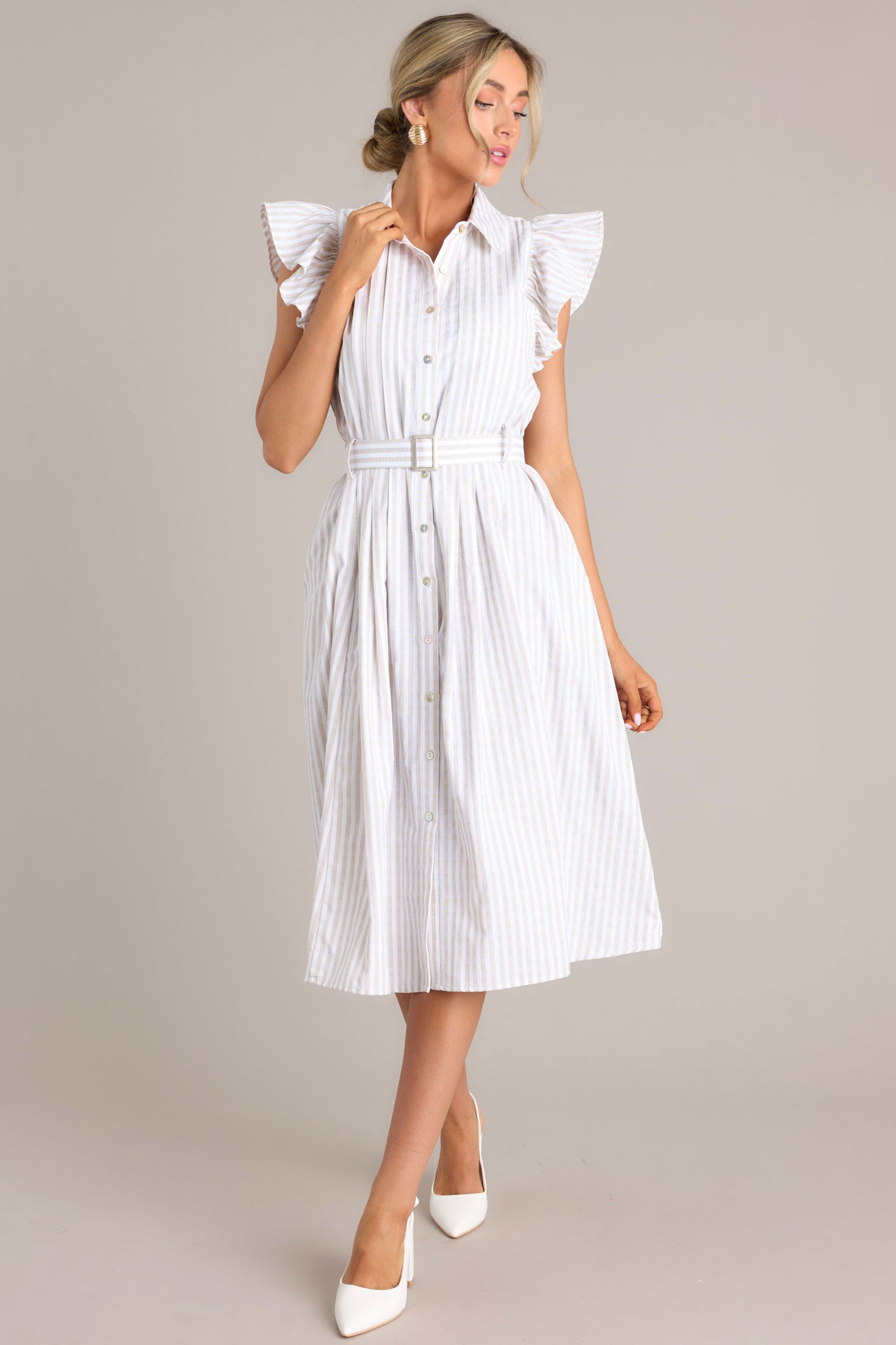 Full front view of this dress that features a collared neckline, ruffle sleeves, a full button front, pleated details throughout the front, belt loops, an adjustable belt with a functional buckle, and hip pockets.